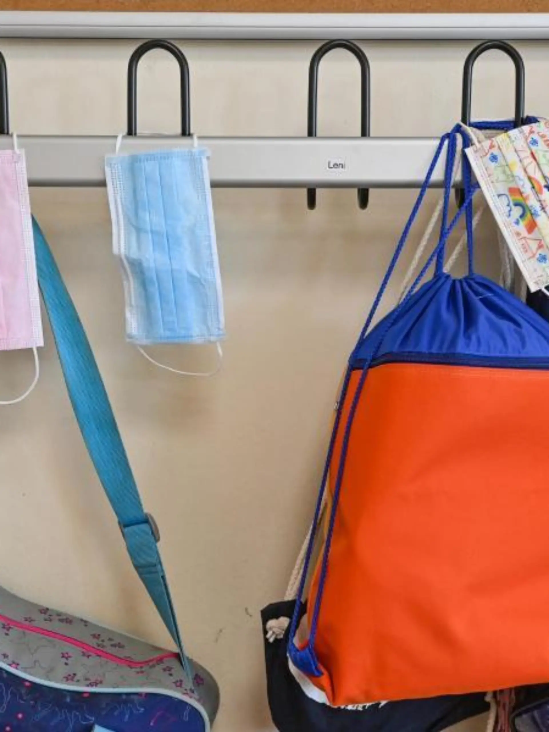 Masken hängen zusammen mit Taschen und Rucksäcken an Kleiderhaken