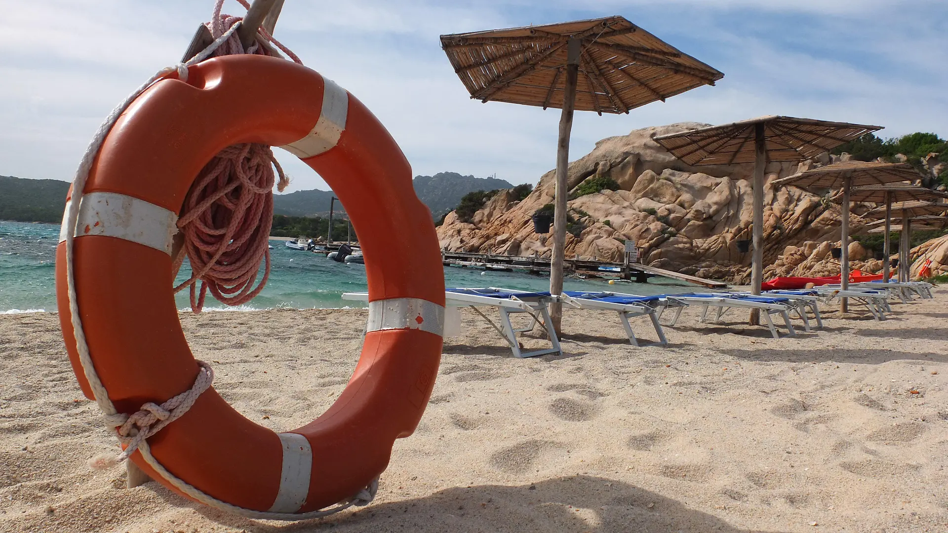 ARCHIV - 13.05.2012, Italien, Sardinien: Ein Rettungsring stehen neben Sonnenliegen und Schirmen am Sandstrand von Capriccioli. (zu dpa Sand mitnehmen verboten - Warnung an deutsche Sardinien-Touristen vom 03.08.2018) Foto: Marcus Brandt/dpa +++ dpa-Bildfunk +++