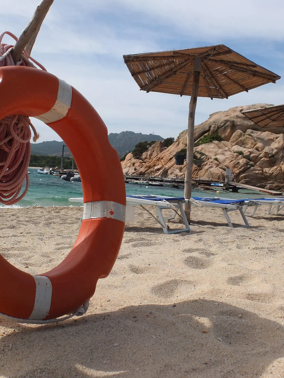 ARCHIV - 13.05.2012, Italien, Sardinien: Ein Rettungsring stehen neben Sonnenliegen und Schirmen am Sandstrand von Capriccioli. (zu dpa Sand mitnehmen verboten - Warnung an deutsche Sardinien-Touristen vom 03.08.2018) Foto: Marcus Brandt/dpa +++ dpa-Bildfunk +++