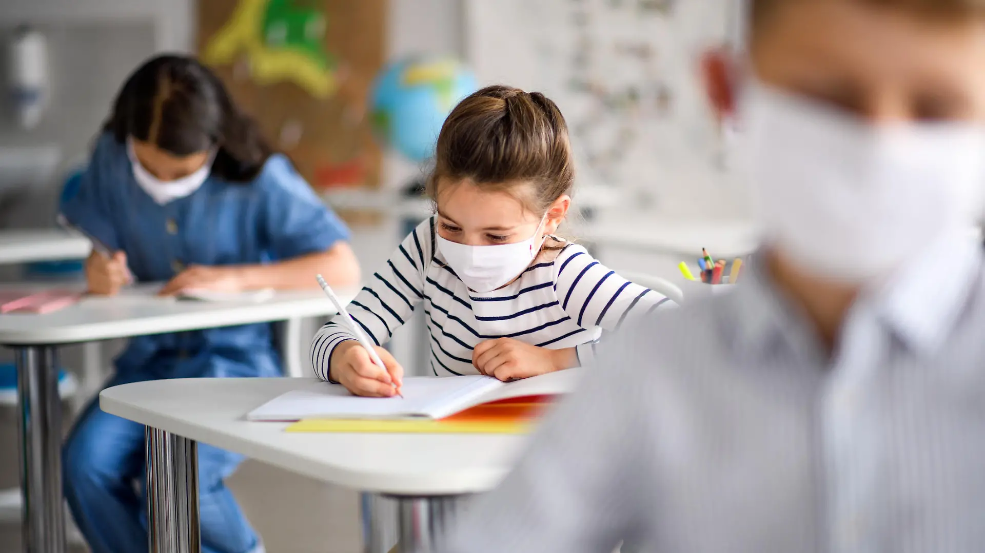Schüler sitzen mit Corona-Maske im Klassenzimmer.