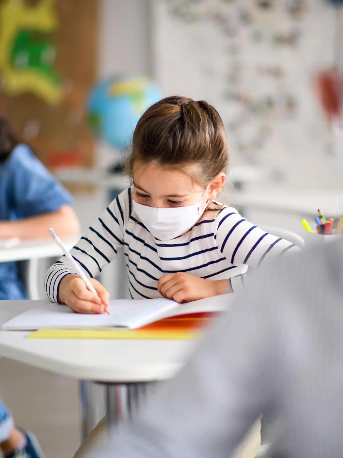 Schüler sitzen mit Corona-Maske im Klassenzimmer.