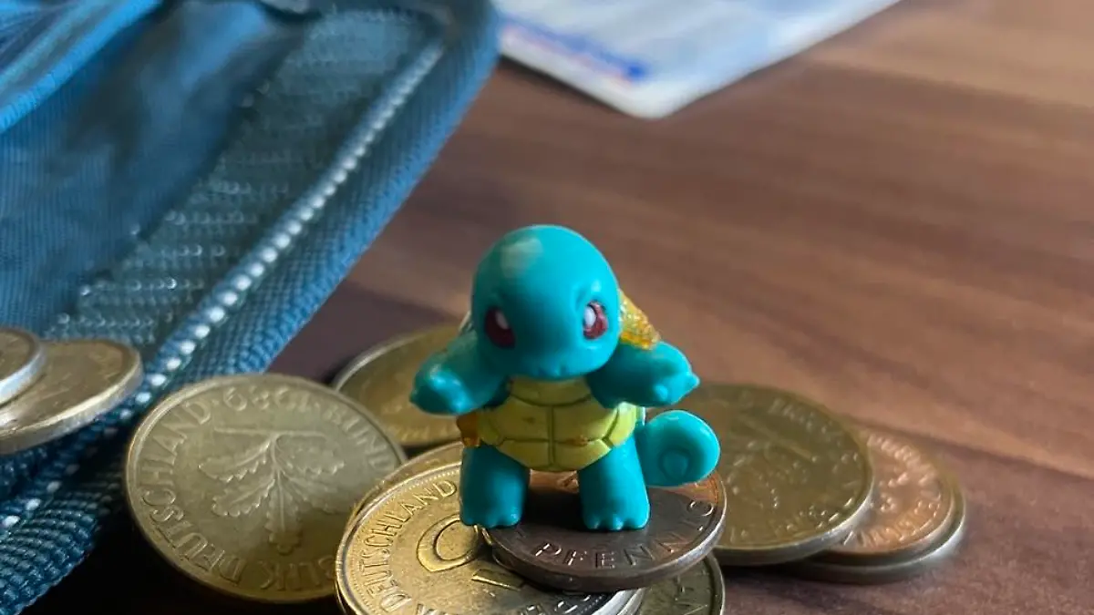 HANDOUT - 05.05.2023, Nordrhein-Westfalen, Hamm: In einem Kinderportemonnaie befinden sich Pfennige und eine Pokémon-Figur. Nach 23 Jahren ist in einem Kino in Hamm ein Portemonnaie wieder aufgetaucht, das ein kleiner Besucher einmal während einer Vorstellung verloren hatte. Mit einem Facebook-Post suchten die Betreiber nach dem Besitzer der Geldbörse - und fanden ihn. (Zu dpa: «Nach 23 Jahren: Portemonnaie zwischen Kinosesseln gefunden») Foto: Cineplex Hamm/dpa - ACHTUNG: Nur zur redaktionellen Verwendung im Zusammenhang mit der aktuellen Berichterstattung und nur mit vollständiger Nennung des vorstehenden Credits +++ dpa-Bildfunk +++