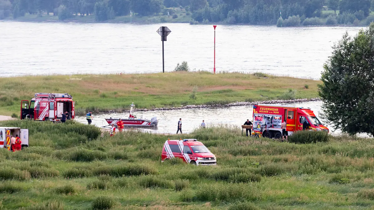 16.06.2021, Nordrhein-Westfalen, Duisburg: Einsatzkräfte der Polizei, Feuerwehr und DRLG arbeiten am Ufer des Rheins. Nach einem möglichen Badeunfall ist eine Person gerettet worden. Zwei weitere werden noch vermisst. Foto: Marcel Kusch/dpa +++ dpa-Bildfunk +++