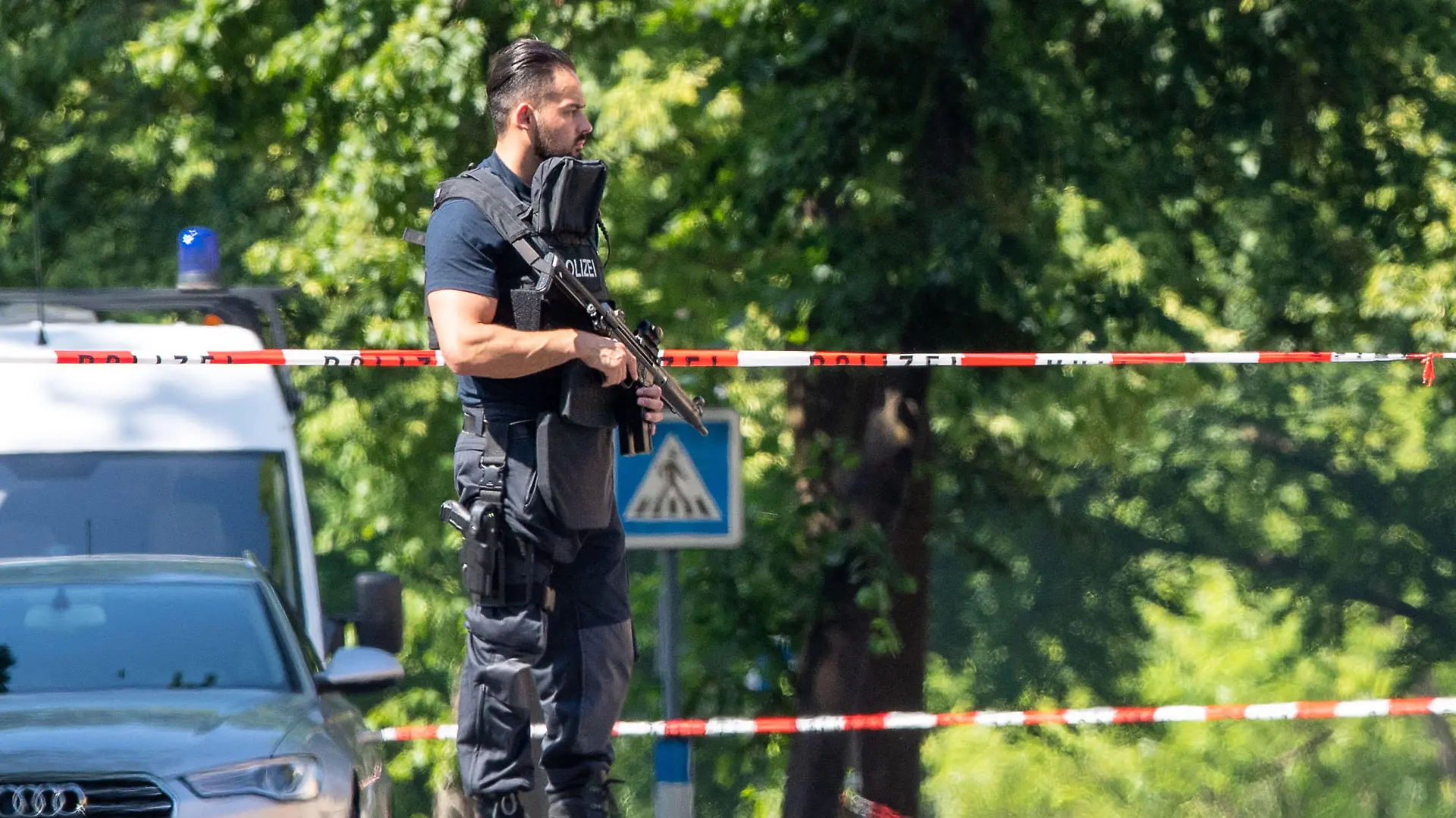 17.06.2021, Nordrhein-Westfalen, Espelkamp: Ein Polizist mit Schutzweste und Gewehr steht an einer Absperrung in Espelkamp. In Espelkamp sind nach Angaben der Bielefelder Polizei zwei Menschen erschossen worden. Der Täter befinde sich noch auf der Flucht, sagte ein Polizeisprecher der Deutschen Presse-Agentur am Donnerstag. Foto: Lino Mirgeler/dpa +++ dpa-Bildfunk +++