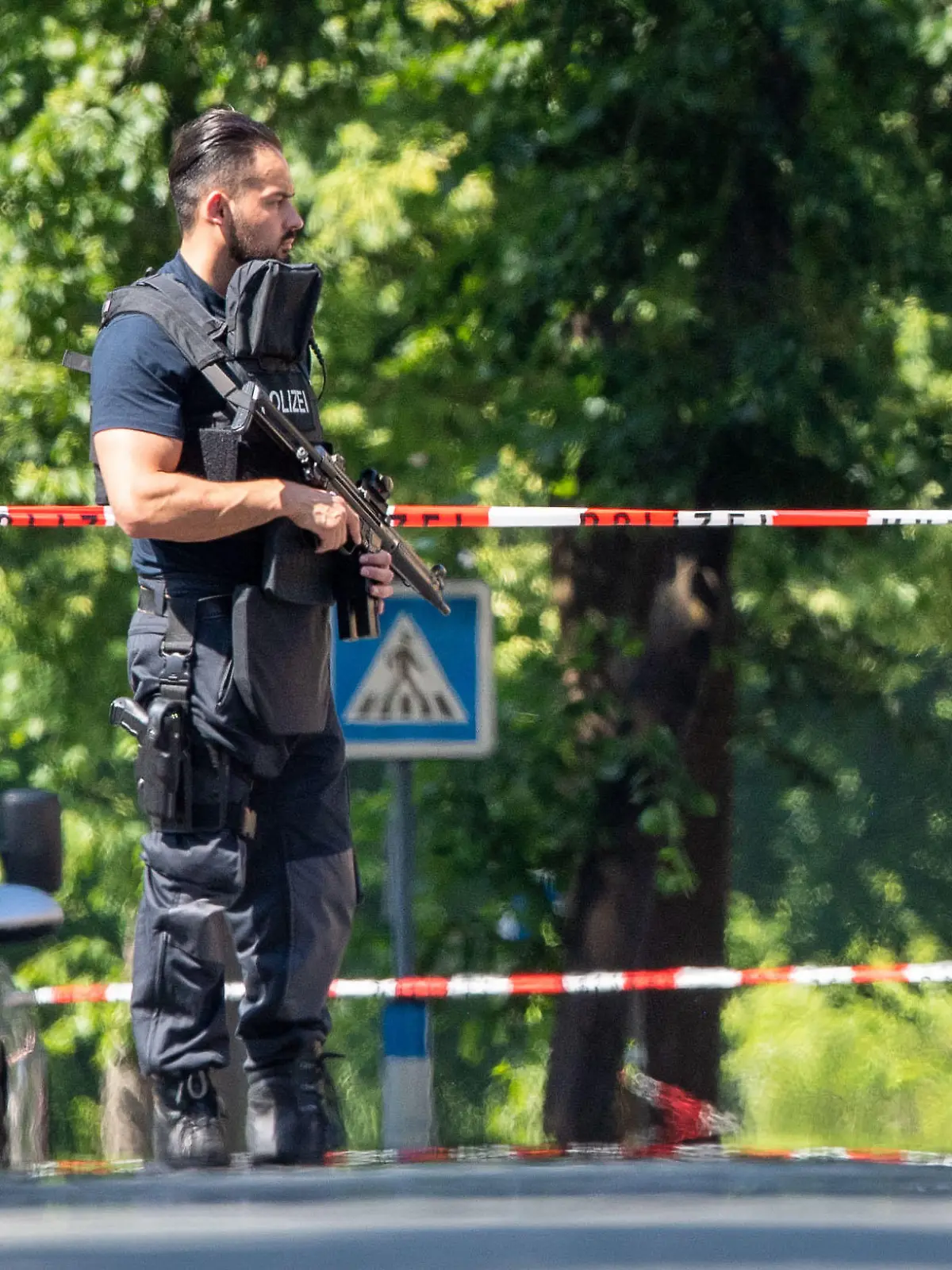 17.06.2021, Nordrhein-Westfalen, Espelkamp: Ein Polizist mit Schutzweste und Gewehr steht an einer Absperrung in Espelkamp. In Espelkamp sind nach Angaben der Bielefelder Polizei zwei Menschen erschossen worden. Der Täter befinde sich noch auf der Flucht, sagte ein Polizeisprecher der Deutschen Presse-Agentur am Donnerstag. Foto: Lino Mirgeler/dpa +++ dpa-Bildfunk +++