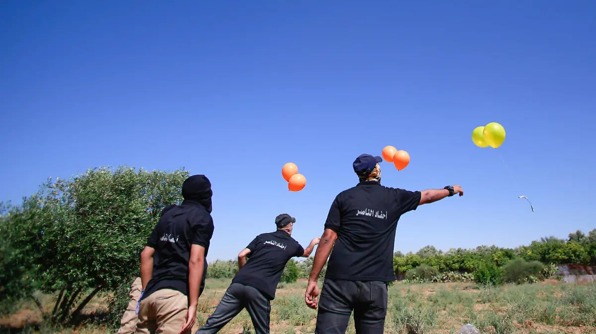 June 15, 2021, Gaza, Palestine: Masked Palestinians launch incendiary balloons from the Gaza Strip towards Israel..Palestinian activists launch incendiary balloons from the Gaza Strip towards Israel in protest to the flag march in East Jerusalem happening now and concerns of a fresh outbreak of violence as some 5,000 right-wing nationalists are due to parade through Jerusalem s Old City waving Israel s blue and white flag. Gaza incendiary balloons burned farmland in at least 13 different locations reports.Israeli media. Gaza Palestine - ZUMAs197 20210615_zaa_s197_100 Copyright: xAhmedxZakotx