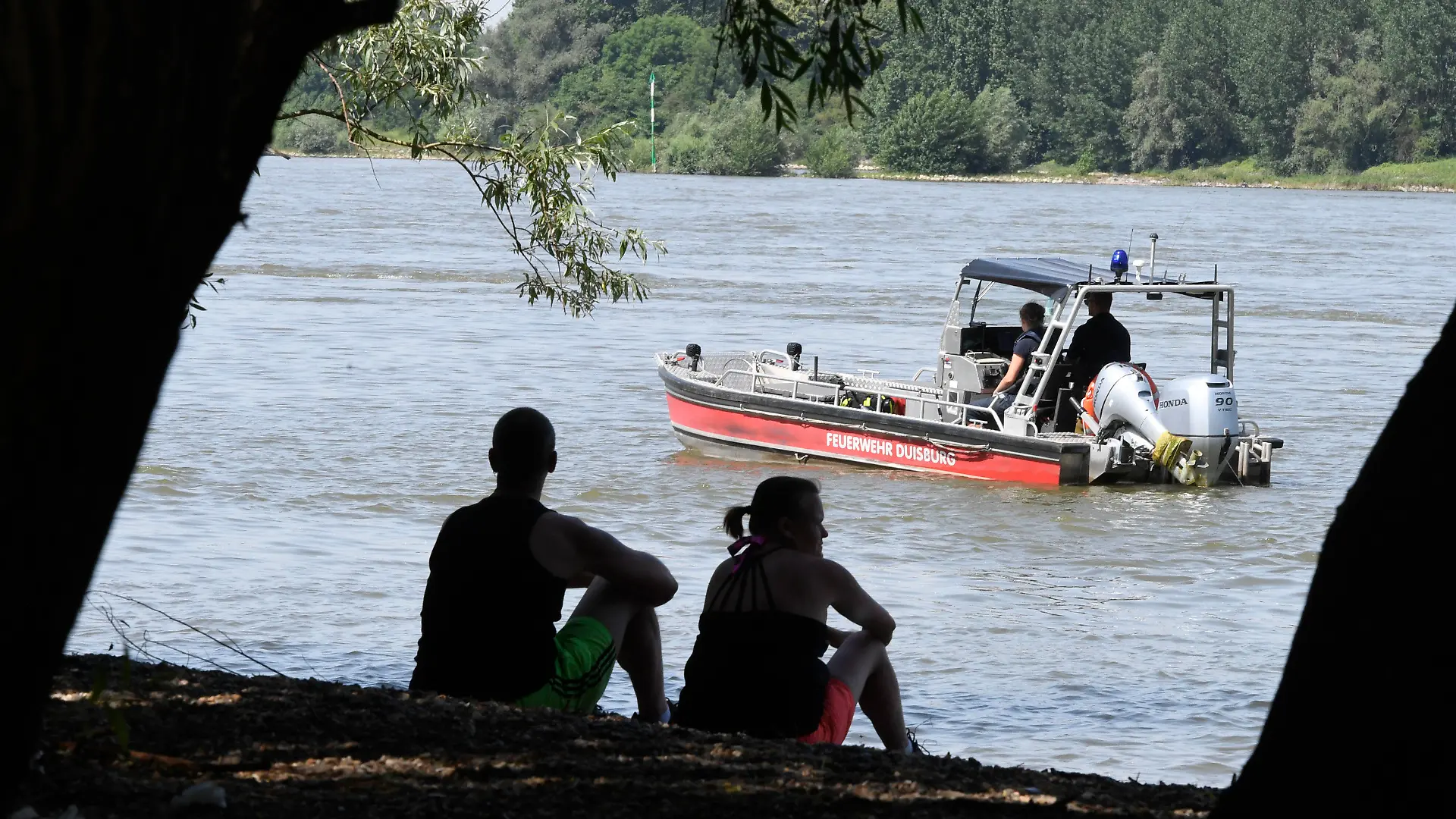 17.06.2021, Nordrhein-Westfalen, Duisburg: Einsatzkräfte der Feuerwehr intensivieren mittels Tauchern, Hubschraubern und Rettungsbooten, die Suche nach zwei vermissten Mädchen, die am Mittwochabend im Fluss ein erfrischendes Bad nehmen wollten. Beim Baden im Rhein ist am Mittwochabend in Duisburg eine 17-Jährige ertrunken. Nach zwei Mädchen, die zusammen mit der 17-Jährigen ins Wasser gegangenen waren, suchte die Polizei am Donnerstagmorgen noch mit Rettungsbooten und Hubschraubern, wie eine Sprecherin mitteilte. Foto: Roberto Pfeil/dpa +++ dpa-Bildfunk +++