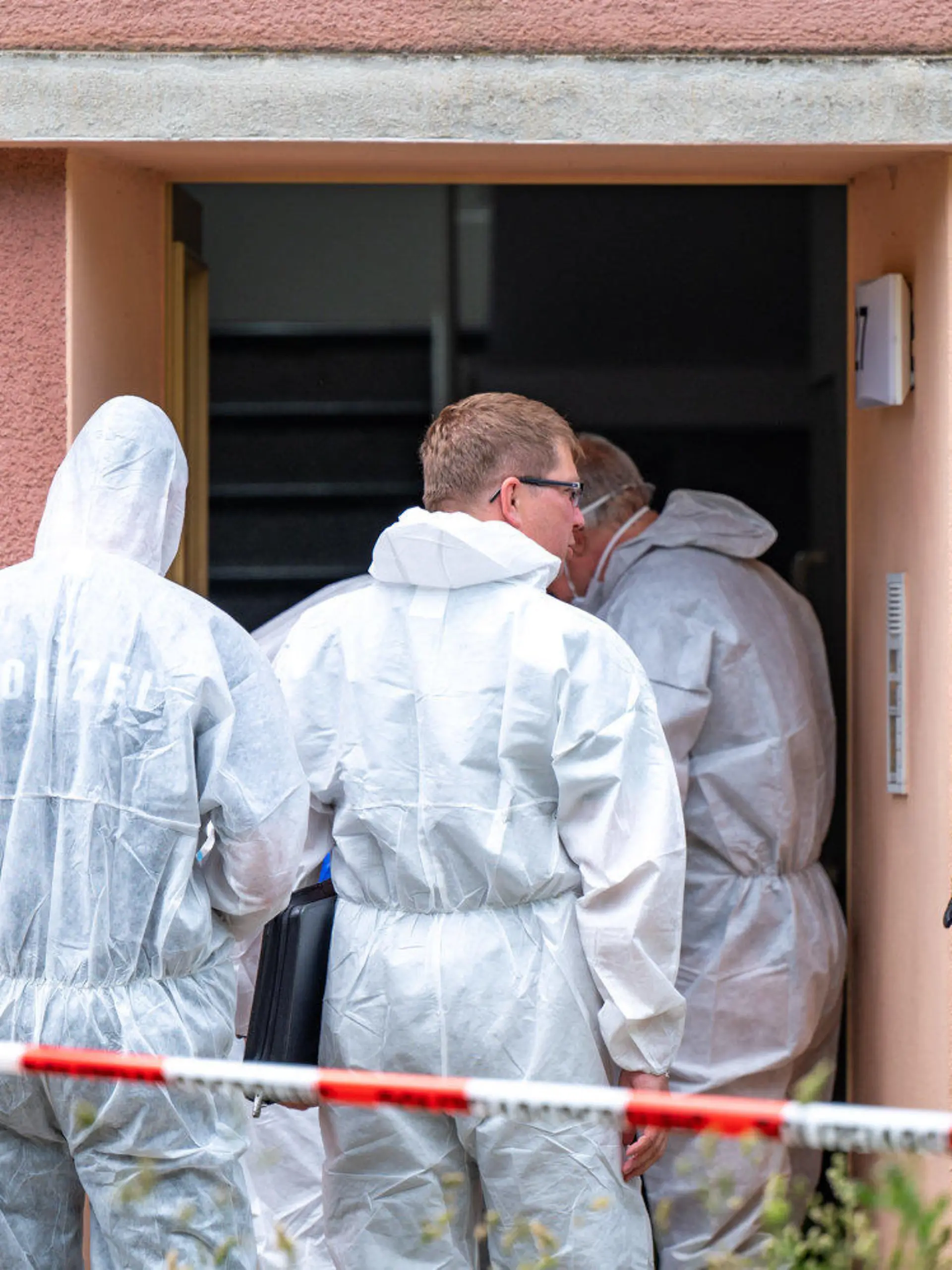15.06.2021, Sachsen, Weimar: Kriminalbeamte stehen vor einem Haus, das mit rot-weißem Flatterband abgesperrt ist. In dem Gebäude wurde eine männliche Leiche gefunden. Die Ermittler gehen von einem Tötungsdelikt aus. Foto: Johannes Krey/dpa-Zentralbild/dpa +++ dpa-Bildfunk +++