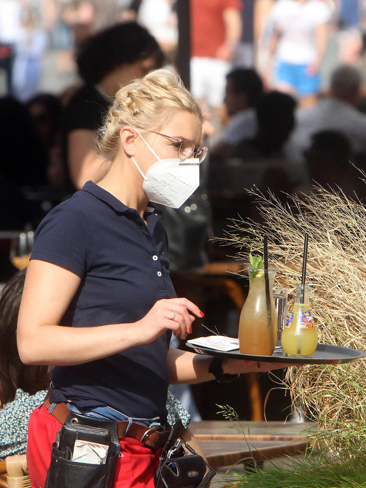Aufgrund anhaltend niedriger Inzidenzen in Würzburg dürfen gastronomische Betriebe ihren Außenbereich auch ohne negativen Coronatest wieder öffnen. Eine Kellnerin eines Restaurants in der Innenstadt liefert auf ihrem Tablett Getränke an Gäste an einem vollbesetzten Tisch, Bayern, Deutschland *** Due to persistently low incidences in Würzburg, gastronomic establishments are allowed to reopen their outdoor areas even without a negative coronatest A waitress at a downtown restaurant delivers drinks on her tray to patrons at a crowded table, Bavaria, Germany 