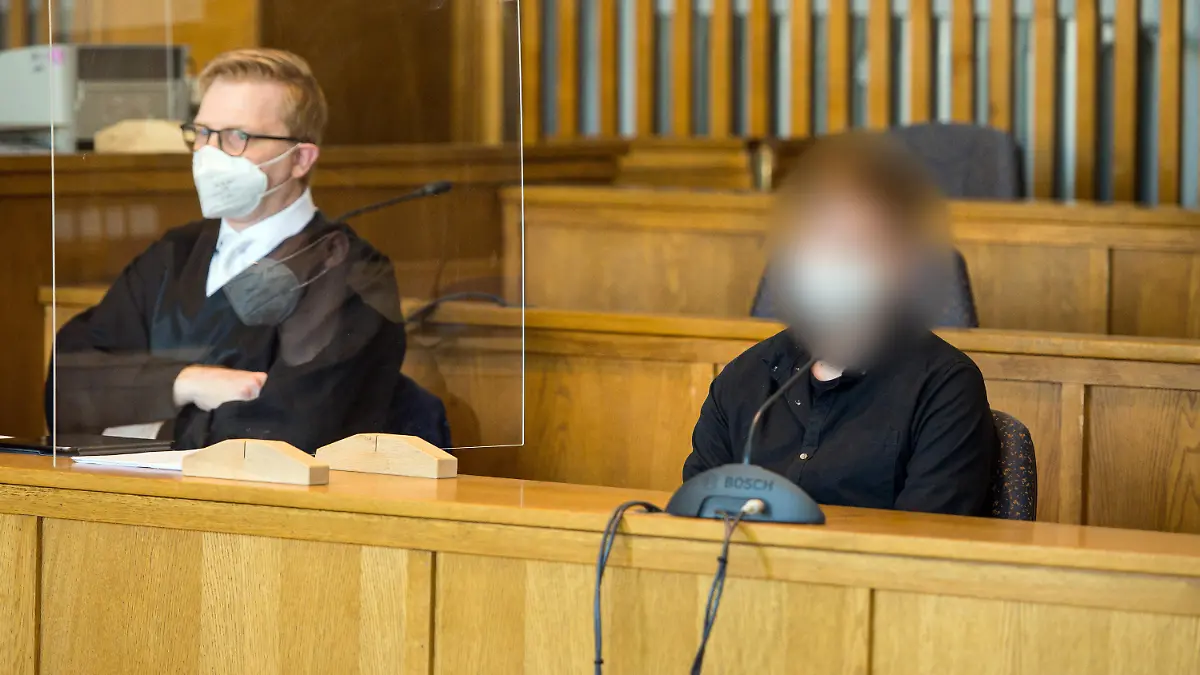 16.06.2021, Saarland, Saarbrücken: Der Angeklagte sitzt im Gerichtssaal des Landgerichts Saarbrücken neben seinem Anwalt Pascal Bastuck (l). Wegen Mordes durch rücksichtlose Fahrweise musssich der 30-Jährige verantworten. Er soll im August 2017 mitten in Saarwellingen mit Tempo 130 ungebremst auf ein Auto gerast sein. Dabei wurden eine Mutter und deren Tochter, die in dem Wagen saßen, tödlich verletzt. Foto: Oliver Dietze/dpa - ACHTUNG: Person(en) wurde(n) aus rechtlichen Gründen gepixelt +++ dpa-Bildfunk +++