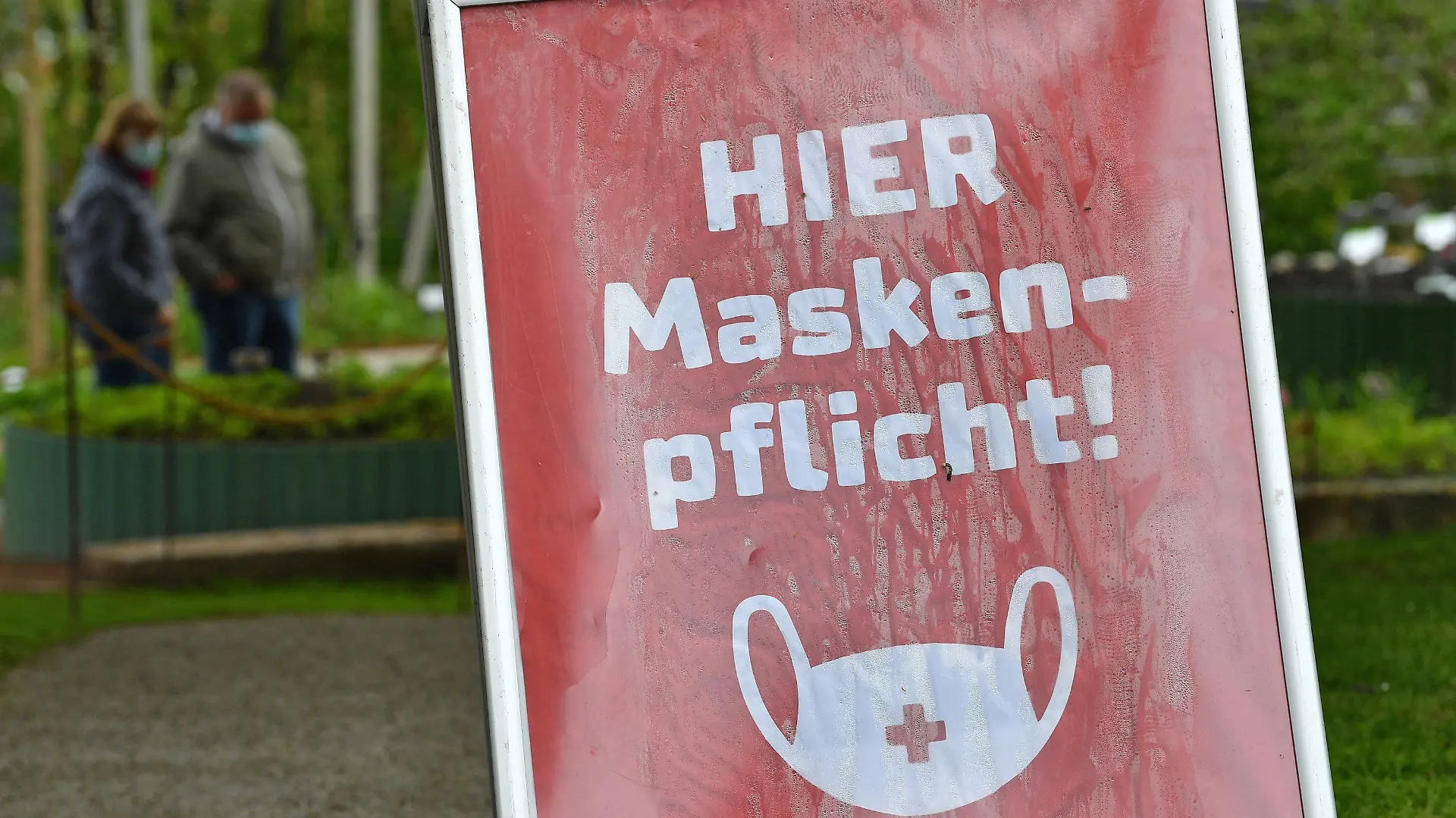 20.05.2021, Thüringen, Erfurt: «Hier Maskenpflicht» steht auf dem Schild in einem kleinen Bereich auf dem Gelände der Bundesgartenschau im egapark. Nachdem rund einen Monat eine Testpflicht für einen Besuch der Bundesgartenschau (Buga) galt, entfällt diese ab dem 21. Mai. Für die derzeit geöffneten Freiflächen ist dann kein amtlicher negativer Corona-Test oder Impfnachweis mehr notwendig. Das ist aufgrund der anhaltenden Sieben-Tage-Inzidenz von unter 100 in der thüringischen Landeshauptstadt möglich. Foto: Martin Schutt/dpa-Zentralbild/dpa +++ dpa-Bildfunk +++
