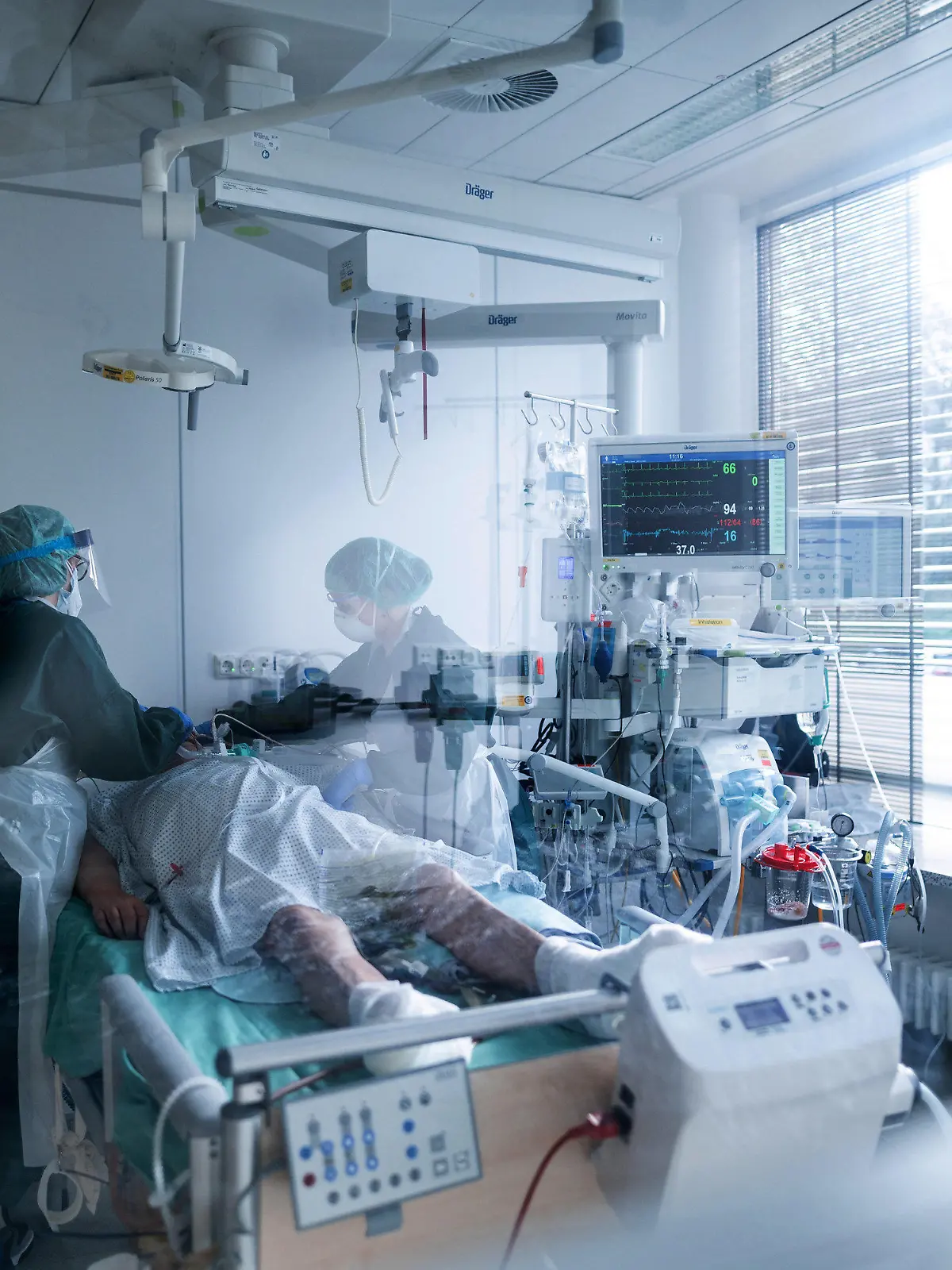 ARCHIV - 28.10.2020, Nordrhein-Westfalen, Essen: Mitarbeiterinnen der Pflege in Schutzausrüstung betreut einen Corona-Patienten. Karl-Josef Laumann (CDU), Minister für Arbeit, Gesundheit und Soziales des Landes Nordrhein-Westfalen, informiert am Mittwoch über die aktuelle Lage und Maßnahmen der NRW-Landesregierung im Rahmen der Corona-Pandemie. Foto: Fabian Strauch/dpa - ACHTUNG: Teile des Bildes wurden aus rechtlichen Gründen gepixelt +++ dpa-Bildfunk +++