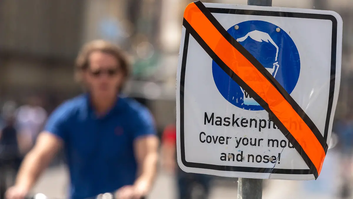 11.06.2021, Bayern, München: Ein mit orangen Klebeband durchgestrichenes Schild mit der Aufschrift «Maskenpflicht - Cover your mouth and nose!» steht in der Innenstadt am Straßenrand. Die generelle Maskenpflicht, in einem gekennzeichneten Bereich der Altstadt zwischen 9 und 21 Uhr galt, wurde aufgehoben. Foto: Peter Kneffel/dpa +++ dpa-Bildfunk +++