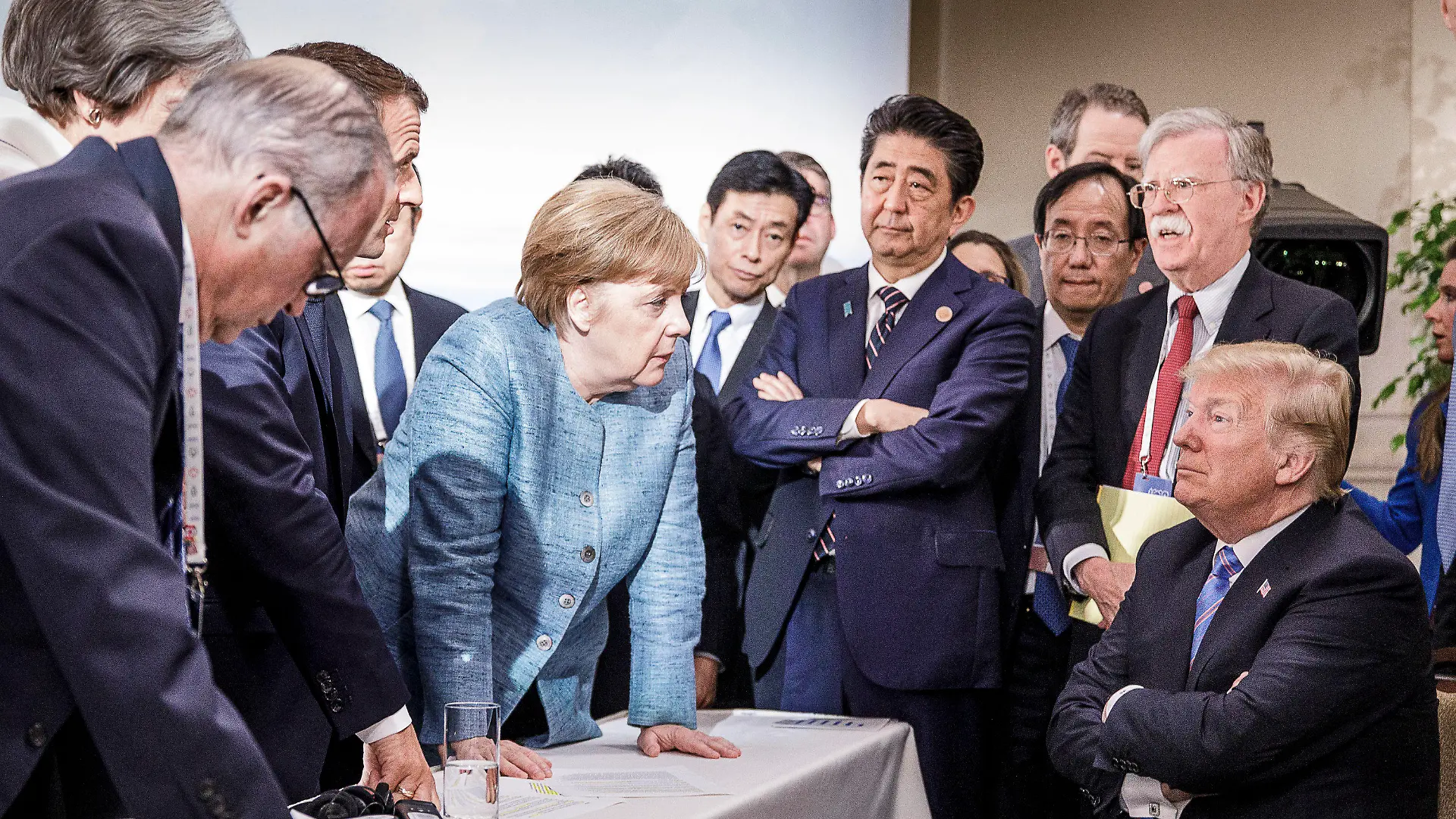 HANDOUT - ARCHIV - 09.06.2018, Charlevoix, La Malbaie, Quebec, Kanada: Bundeskanzlerin Angela Merkel (CDU, M) spricht mit US-Präsident Donald Trump (r) während der Beratungen am Rande der offiziellen Tagesordnung. Emmanuel Macron (2.v.l), Präsident von Frankreich, Shinzo Abe (4.v.r), Ministerpräsident von Japan, und John Bolton, Nationaler Sicherheitsberater der USA, verfolgen das Gespräch. (zu dpa «Trump kontert Merkel-Foto: Nicht nur schlechte Bilder zeigen» vom 16.06.2018) Foto: Jesco Denzel/Bundesregierung /dpa - ACHTUNG: Nur zur redaktionellen Verwendung und nur mit vollständiger Nennung des vorstehenden Credits +++ dpa-Bildfunk +++