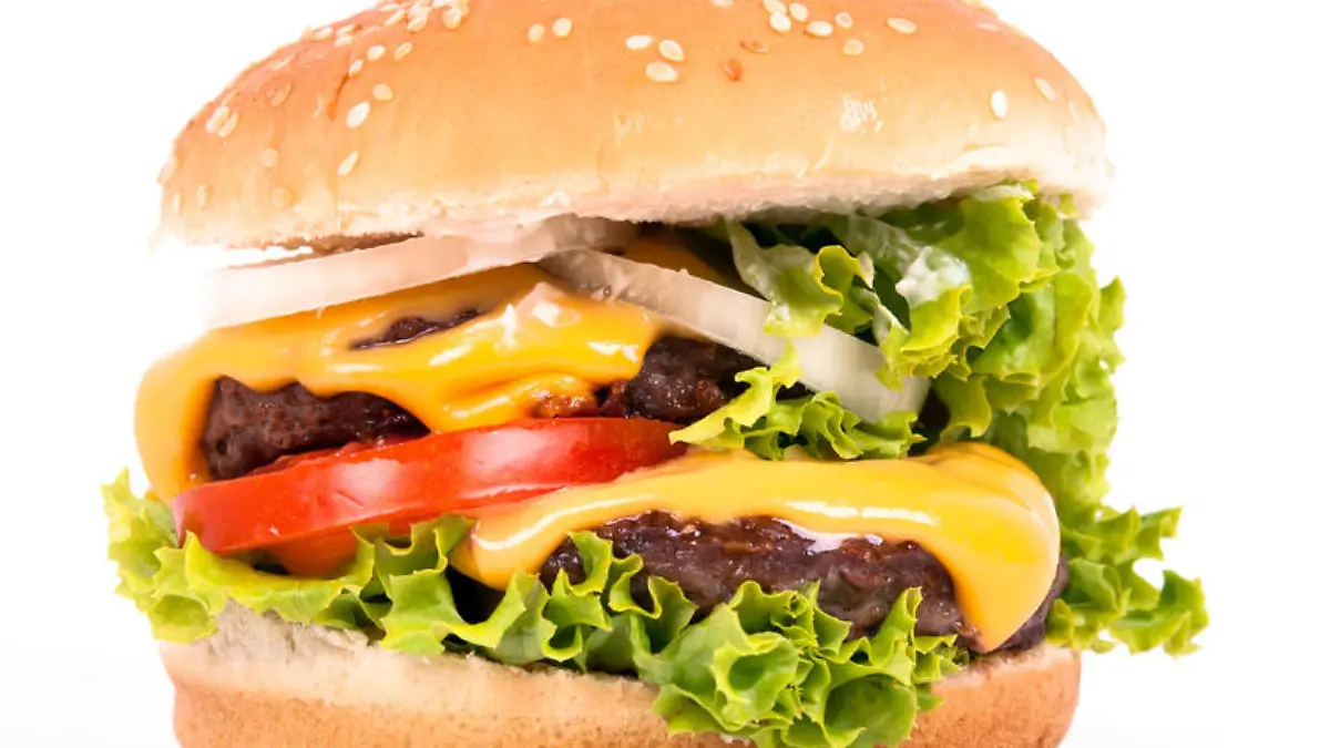 ein Cheeseburger mit Tomate, Salat und Zwiebeln vor weißem Hintergrund
