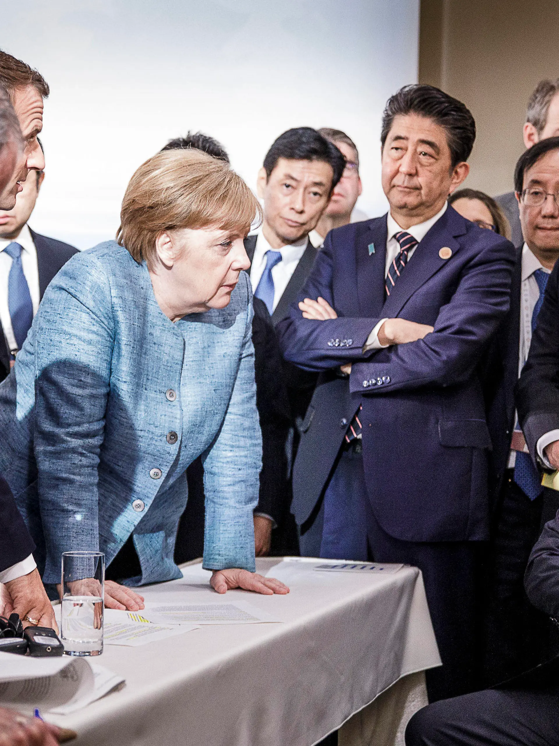 dpatopbilder - HANDOUT - 09.06.2018, Charlevoix, La Malbaie, Quebec, Kanada: Bundeskanzlerin Angela Merkel (CDU, M) spricht mit US-Präsident Donald Trump (r) während der Beratungen am Rande der offiziellen Tagesordnung. Emmanuel Macron (2.v.l), Präsident von Frankreich, Shinzo Abe (4.v.r), Ministerpräsident von Japan, und John Bolton, Nationaler Sicherheitsberater der USA, verfolgen das Gespräch. Foto: Jesco Denzel/Bundesregierung /dpa - ACHTUNG: Nur zur redaktionellen Verwendung und nur mit vollständiger Nennung des vorstehenden Credits +++ dpa-Bildfunk +++