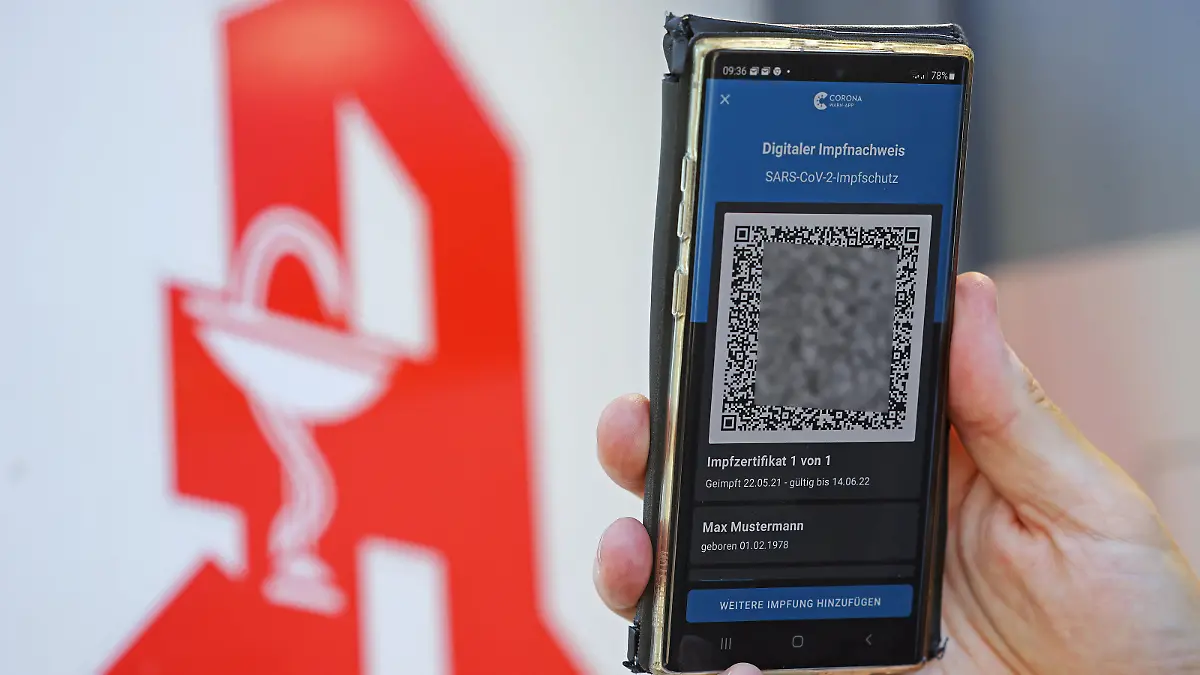 Der digitale Impfnachweis ist vor dem Apotheken-Logo auf einem Smartphone zu sehen.