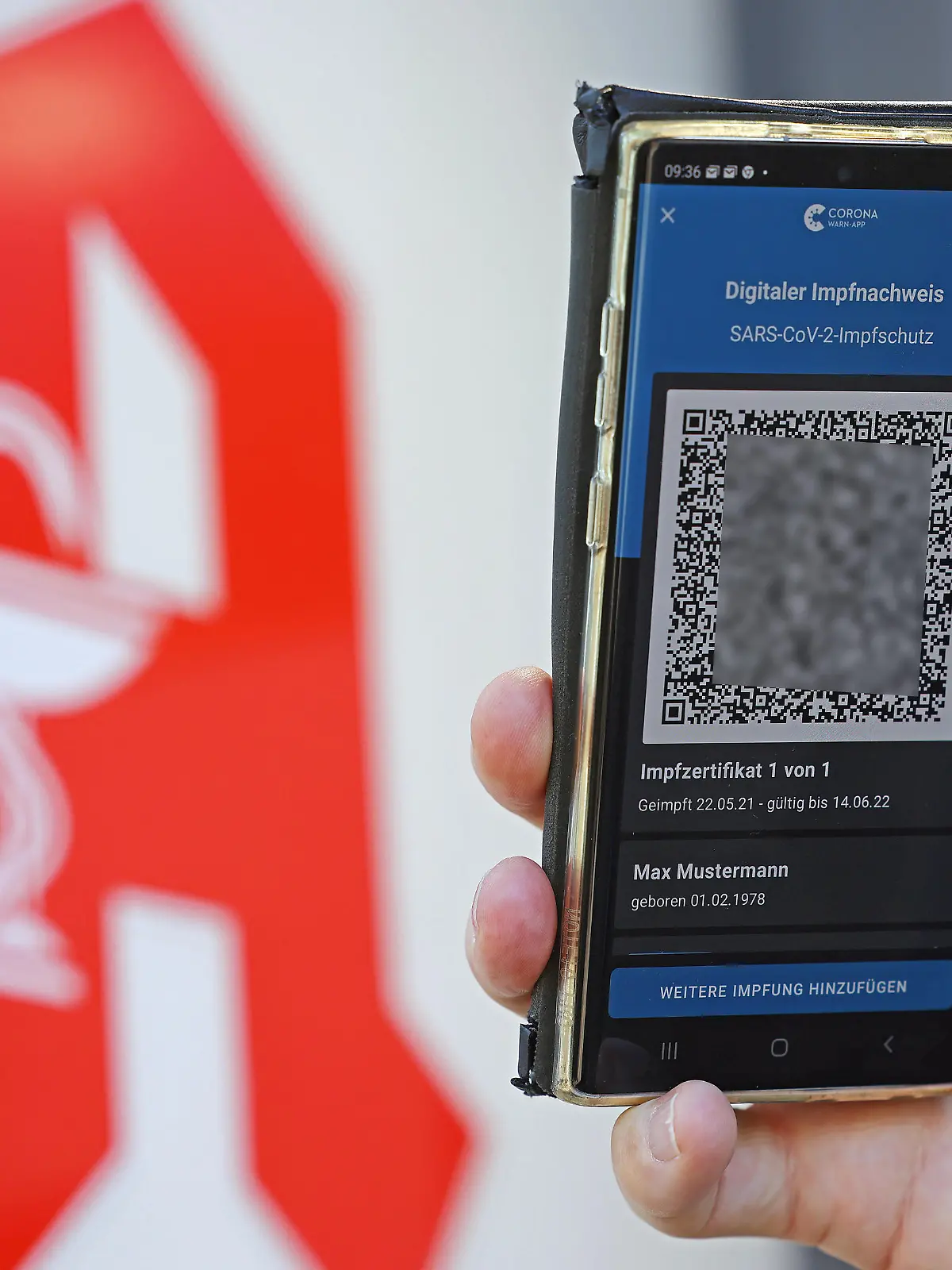 Der digitale Impfnachweis ist vor dem Apotheken-Logo auf einem Smartphone zu sehen.