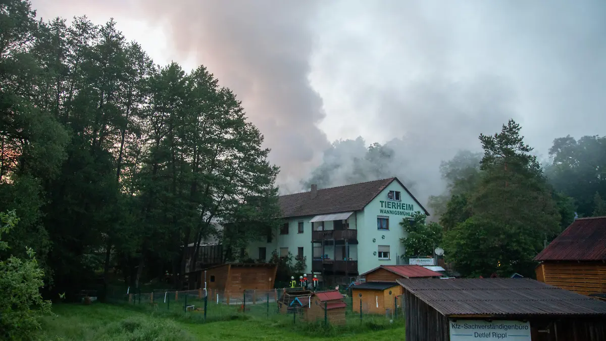09.06.2021, Münnerstadt: Einsatzkräfte der Feuerwehr gehen an einem Gebäude des Tierheims entlang. Bei einem Brand in einem Tierheim in Unterfranken sind mehr als 100 Tiere ums Leben gekommen. Foto: Stefan Weber/Fuldamedia/dpa +++ dpa-Bildfunk +++