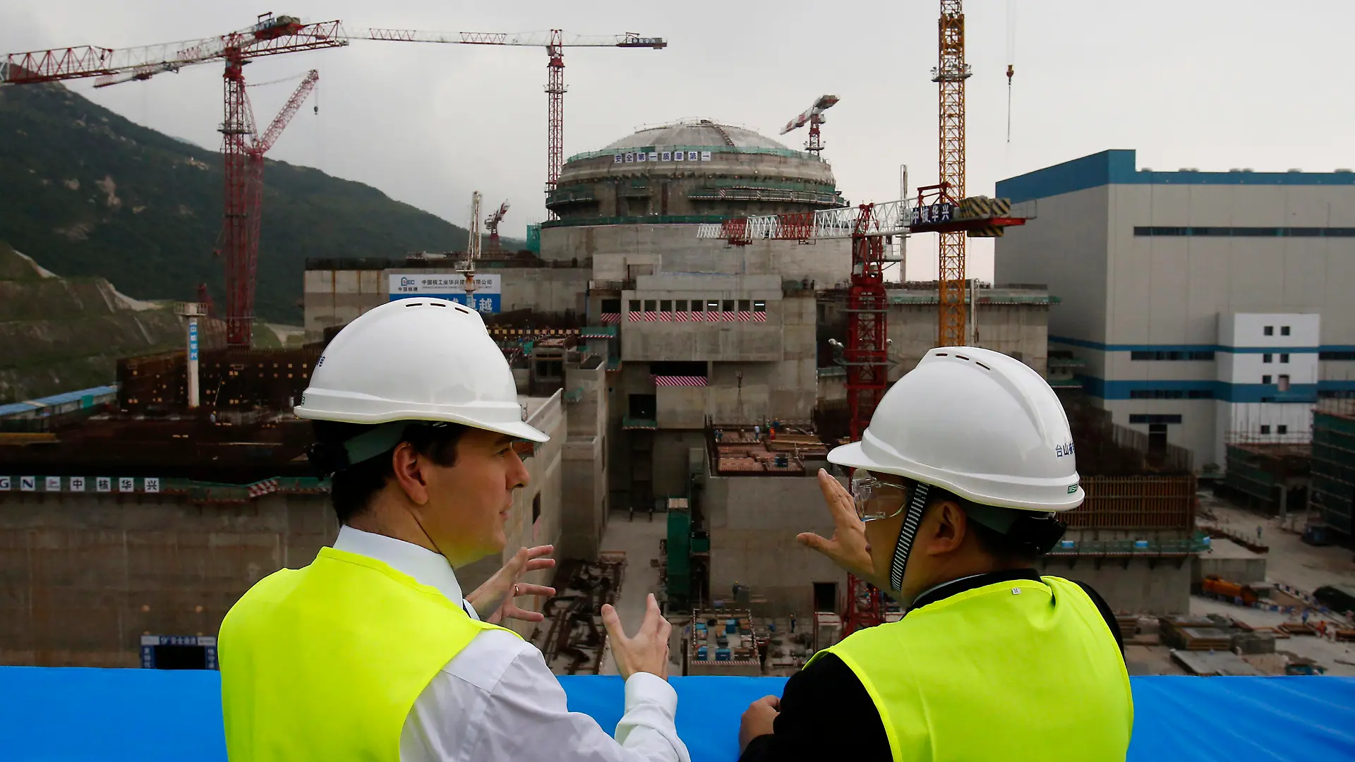 FILE - In this Oct. 17, 2013, file photo, then British Chancellor of the Exchequer George Osborne, left, chats with Taishan Nuclear Power Joint Venture Co. Ltd. General Manager Guo Liming as he inspects a nuclear reactor under construction at the nuclear power plant in Taishan, southeastern China's Guangdong province. The French joint operator of the Chinese nuclear plant near Hong Kong said Monday it is dealing with a “performance issue” but is currently operating within safety limits, following a report of a potential radioactive leak. (AP Photo/Bobby Yip, Pool, File)
