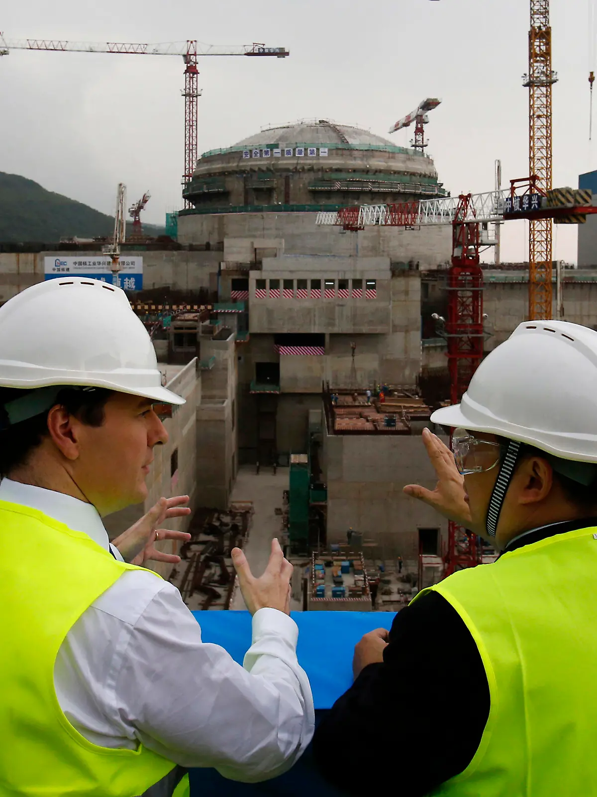 FILE - In this Oct. 17, 2013, file photo, then British Chancellor of the Exchequer George Osborne, left, chats with Taishan Nuclear Power Joint Venture Co. Ltd. General Manager Guo Liming as he inspects a nuclear reactor under construction at the nuclear power plant in Taishan, southeastern China's Guangdong province. The French joint operator of the Chinese nuclear plant near Hong Kong said Monday it is dealing with a “performance issue” but is currently operating within safety limits, following a report of a potential radioactive leak. (AP Photo/Bobby Yip, Pool, File)