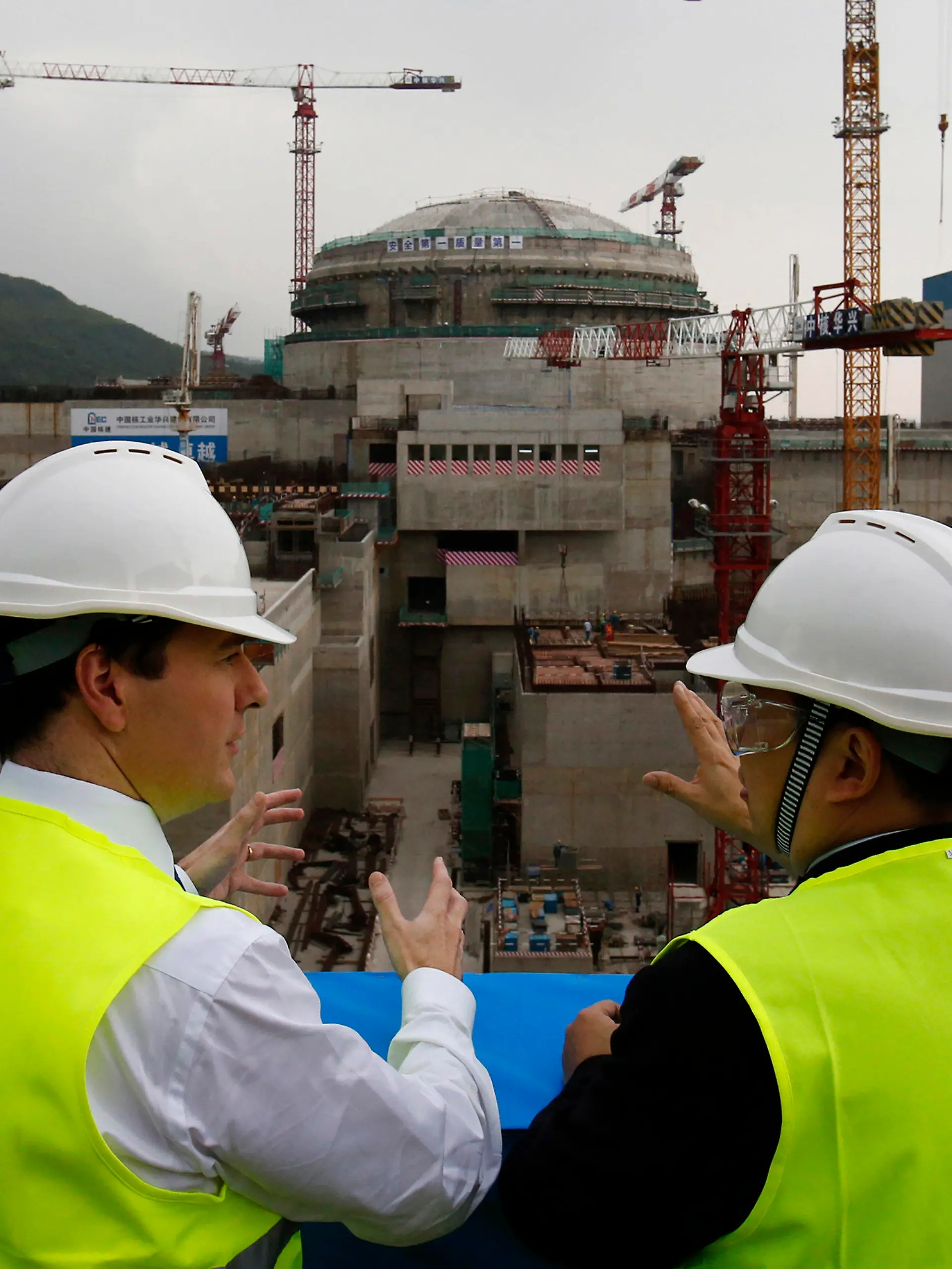 FILE - In this Oct. 17, 2013, file photo, then British Chancellor of the Exchequer George Osborne, left, chats with Taishan Nuclear Power Joint Venture Co. Ltd. General Manager Guo Liming as he inspects a nuclear reactor under construction at the nuclear power plant in Taishan, southeastern China's Guangdong province. The French joint operator of the Chinese nuclear plant near Hong Kong said Monday it is dealing with a “performance issue” but is currently operating within safety limits, following a report of a potential radioactive leak. (AP Photo/Bobby Yip, Pool, File)