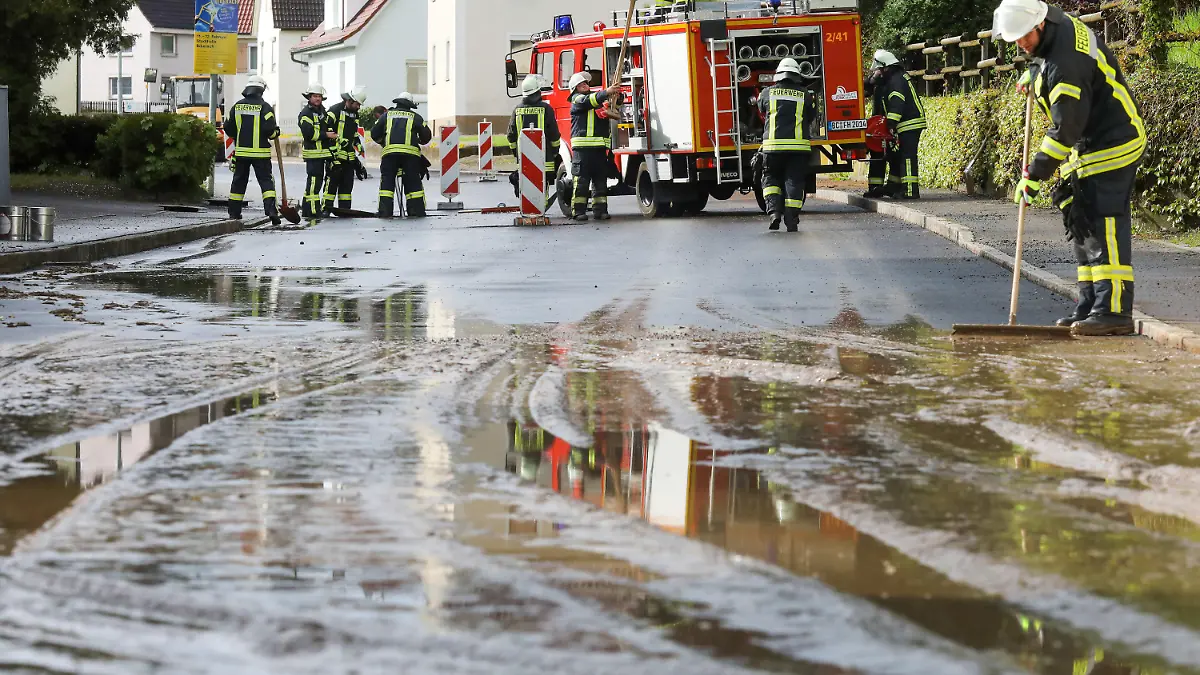 07.05.2023, Baden-Württemberg, Dürmentingen: Einsatzkräfte der Feuerwehr reinigen mit Schaufelader, Wassersauger und Schaufeln eine vom Starkregen überflutete und verschmutzte Straße in Hailtingen. Foto: Thomas Warnack/dpa +++ dpa-Bildfunk +++