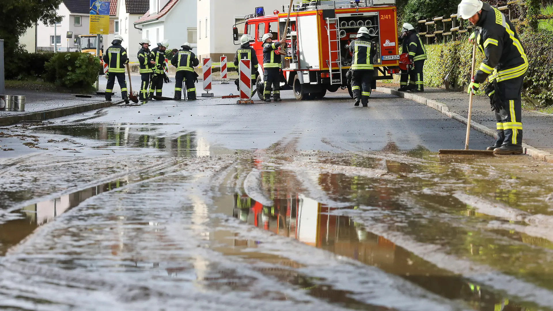 07.05.2023, Baden-Württemberg, Dürmentingen: Einsatzkräfte der Feuerwehr reinigen mit Schaufelader, Wassersauger und Schaufeln eine vom Starkregen überflutete und verschmutzte Straße in Hailtingen. Foto: Thomas Warnack/dpa +++ dpa-Bildfunk +++