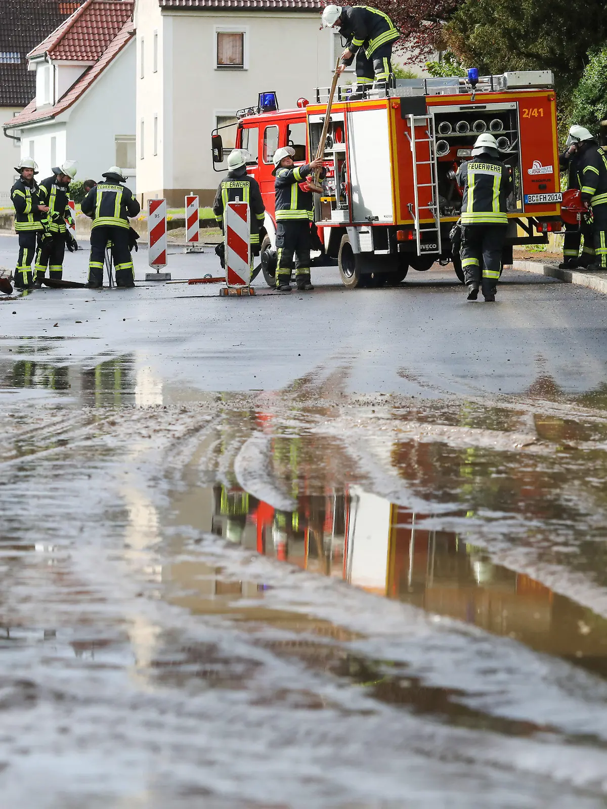 07.05.2023, Baden-Württemberg, Dürmentingen: Einsatzkräfte der Feuerwehr reinigen mit Schaufelader, Wassersauger und Schaufeln eine vom Starkregen überflutete und verschmutzte Straße in Hailtingen. Foto: Thomas Warnack/dpa +++ dpa-Bildfunk +++