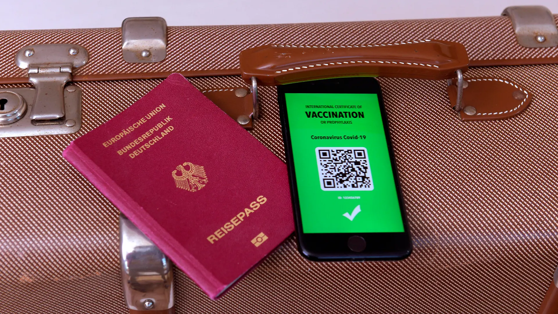 17.03.2021, Symbolbild, Impfung. Ein imaginärer Impfpass in digitaler Form auf dem Smartphone iPhone, bereitgelegt auf einem Reisekoffer mit einem Reisepass. Der digitale Impfpass würde wieder uneingeschränktes Reisen ermöglichen, 17.03.2021, Elektronischer Impfpass für Urlaubsreisen 17.03.2021, Elektronischer Impfpass für Urlaubsreisen *** 17 03 2021, Symbolic image, Vaccination An imaginary vaccination certificate in digital form on the smartphone iPhone, placed at the ready on a travel case with a passport The digital vaccination certificate would once again enable unrestricted travel, 17 03 2021, Electronic vaccination certificate for holiday travel 17 03 2021, Electronic vaccination certificate for holiday travel
