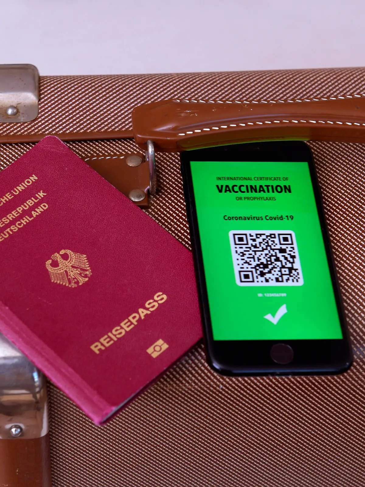 17.03.2021, Symbolbild, Impfung. Ein imaginärer Impfpass in digitaler Form auf dem Smartphone iPhone, bereitgelegt auf einem Reisekoffer mit einem Reisepass. Der digitale Impfpass würde wieder uneingeschränktes Reisen ermöglichen, 17.03.2021, Elektronischer Impfpass für Urlaubsreisen 17.03.2021, Elektronischer Impfpass für Urlaubsreisen *** 17 03 2021, Symbolic image, Vaccination An imaginary vaccination certificate in digital form on the smartphone iPhone, placed at the ready on a travel case with a passport The digital vaccination certificate would once again enable unrestricted travel, 17 03 2021, Electronic vaccination certificate for holiday travel 17 03 2021, Electronic vaccination certificate for holiday travel 