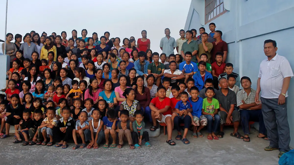 FILE PHOTO: ATTN EDITORS: IMAGE 17 OF 51 OF PICTURE PACKAGE '7 BILLION, 7 STORIES - THE WORLD'S LARGEST FAMILY'. SEARCH 'BAKTAWNG' TO SEE ALL IMAGES Family members of Ziona (R) poses for group photograph outside their residence in Baktawng village in the northeastern Indian state of Mizoram, October 7, 2011. Ziona is the head of a religious sect called "Chana," which allows polygamy and was founded by his father Chana in 1942. Ziona has 39 wives, 94 children and 33 grandchildren. He lives in his 4 storey 100-room house with 181 members of his family. The world's population will reach seven billion on 31 October 2011, according to projections by the United Nations. Picture taken October 7, 2011. REUTERS/Adnan Abidi (INDIA - Tags: SOCIETY) FOR BEST QUALITY IMAGE: ALSO SEE GF2E7BI0OV501/File Photo