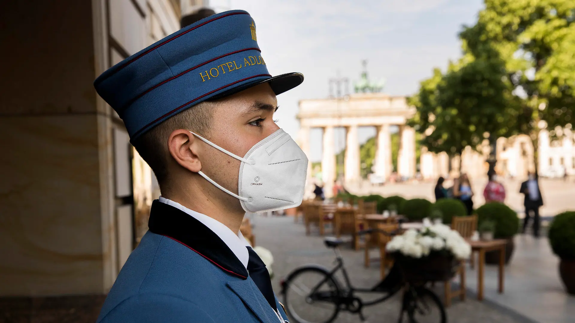 11.06.2021, Berlin: Ein Page steht vor dem Hoteleingang des Hotel Adlon Kempinski am Pariser Platz am Brandenburger Tor. Ab heute können Hotels in Berlin wieder regulär Gäste empfangen. Foto: Carsten Koall/dpa +++ dpa-Bildfunk +++
