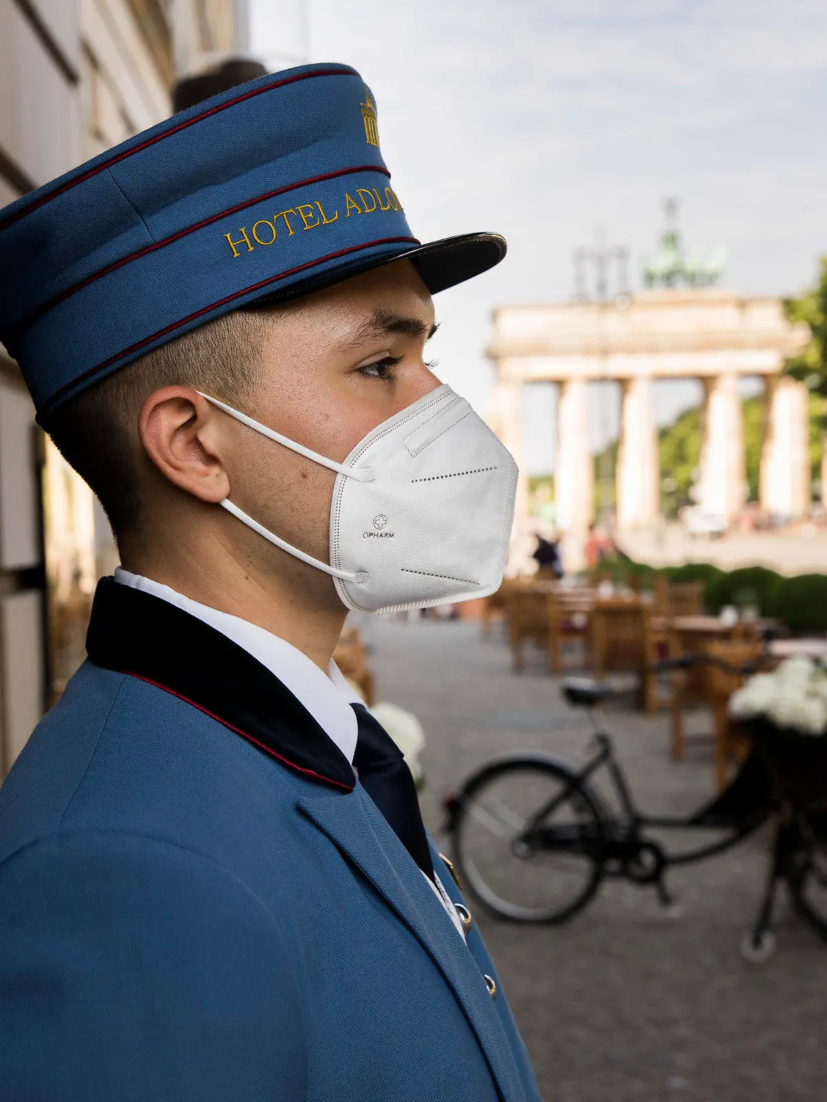 11.06.2021, Berlin: Ein Page steht vor dem Hoteleingang des Hotel Adlon Kempinski am Pariser Platz am Brandenburger Tor. Ab heute können Hotels in Berlin wieder regulär Gäste empfangen. Foto: Carsten Koall/dpa +++ dpa-Bildfunk +++
