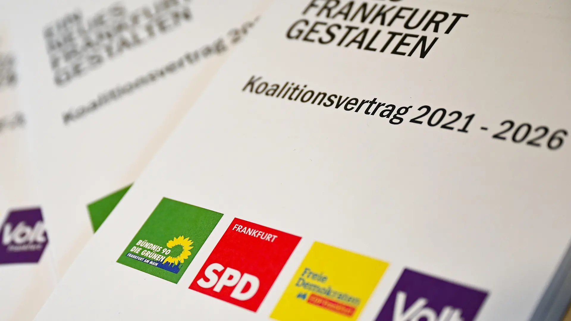 21.05.2021, Hessen, Frankfurt/Main: Exemplare des Koalitionsvertrags 2021-2026 mit dem Motto "Ein neues Frankfurt gestalten" liegen am Rande der Pressekonferenz des "Ampel-Plus"-Bündnisses in Frankfurt auf einem Tisch. Die Koalition aus Bündnis 90/Die Grünen, SPD, FDP sowie der Volt-Partei stellte ihre Koalitionsvereinbarung vor. Aus der Kommunalwahl waren die Grünen erstmals in der größten hessischen Stadt als stärkste Kraft hervorgegangen und hatten sich nach längeren Sondierungen für ein «Ampel Plus»-Bündnis mit insgesamt vier Parteien ausgesprochen. Foto: Arne Dedert/dpa +++ dpa-Bildfunk +++