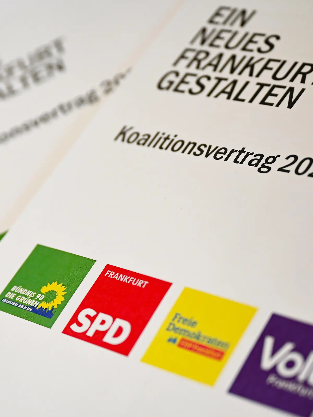 21.05.2021, Hessen, Frankfurt/Main: Exemplare des Koalitionsvertrags 2021-2026 mit dem Motto "Ein neues Frankfurt gestalten" liegen am Rande der Pressekonferenz des "Ampel-Plus"-Bündnisses in Frankfurt auf einem Tisch. Die Koalition aus Bündnis 90/Die Grünen, SPD, FDP sowie der Volt-Partei stellte ihre Koalitionsvereinbarung vor. Aus der Kommunalwahl waren die Grünen erstmals in der größten hessischen Stadt als stärkste Kraft hervorgegangen und hatten sich nach längeren Sondierungen für ein «Ampel Plus»-Bündnis mit insgesamt vier Parteien ausgesprochen. Foto: Arne Dedert/dpa +++ dpa-Bildfunk +++