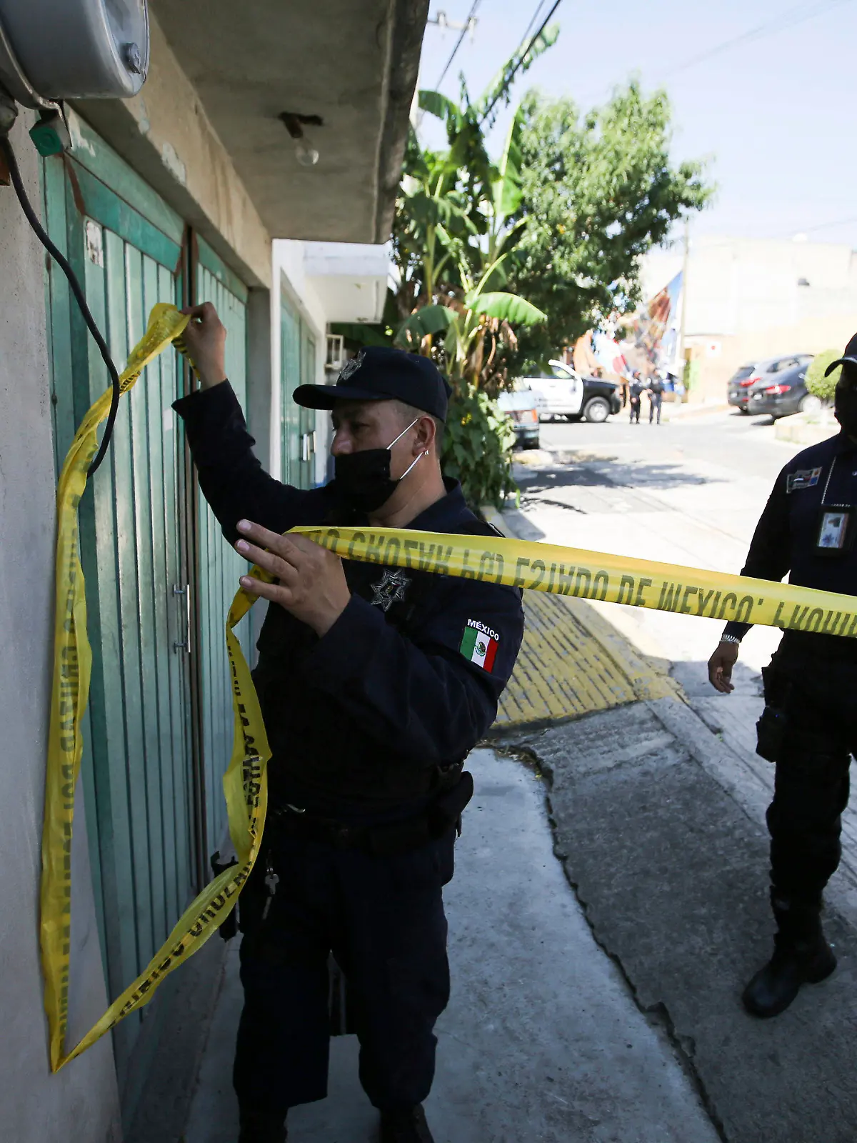 A police officer marks a security perimeter around the house where bones were found under the floor in the Atizapan municipality of the State of Mexico, Thursday, May 20, 2021. Police have turned up bones and other evidence under the floor of the house where a man was arrested for allegedly stabbing a woman to death and hacking up her body. (AP Photo/Fernando Llano)