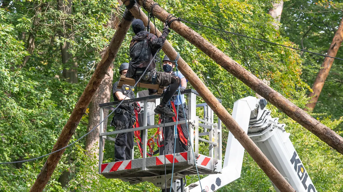 16.09.2020, Hessen, Dannenrod: Die Polizei räumt Barrikaden von Waldbesetzern im Dannenröder Forst in Mittelhessen. Eine Aktivistin sitzt auf einer aus Stämmen errichteten Plattform, während Polizisen von einer Hebenbühne aus versuchen sie zu erreichen. Die Waldbesetzer protestieren gegen den Ausbau der Autobahn 49. Foto: Boris Roessler/dpa +++ dpa-Bildfunk +++