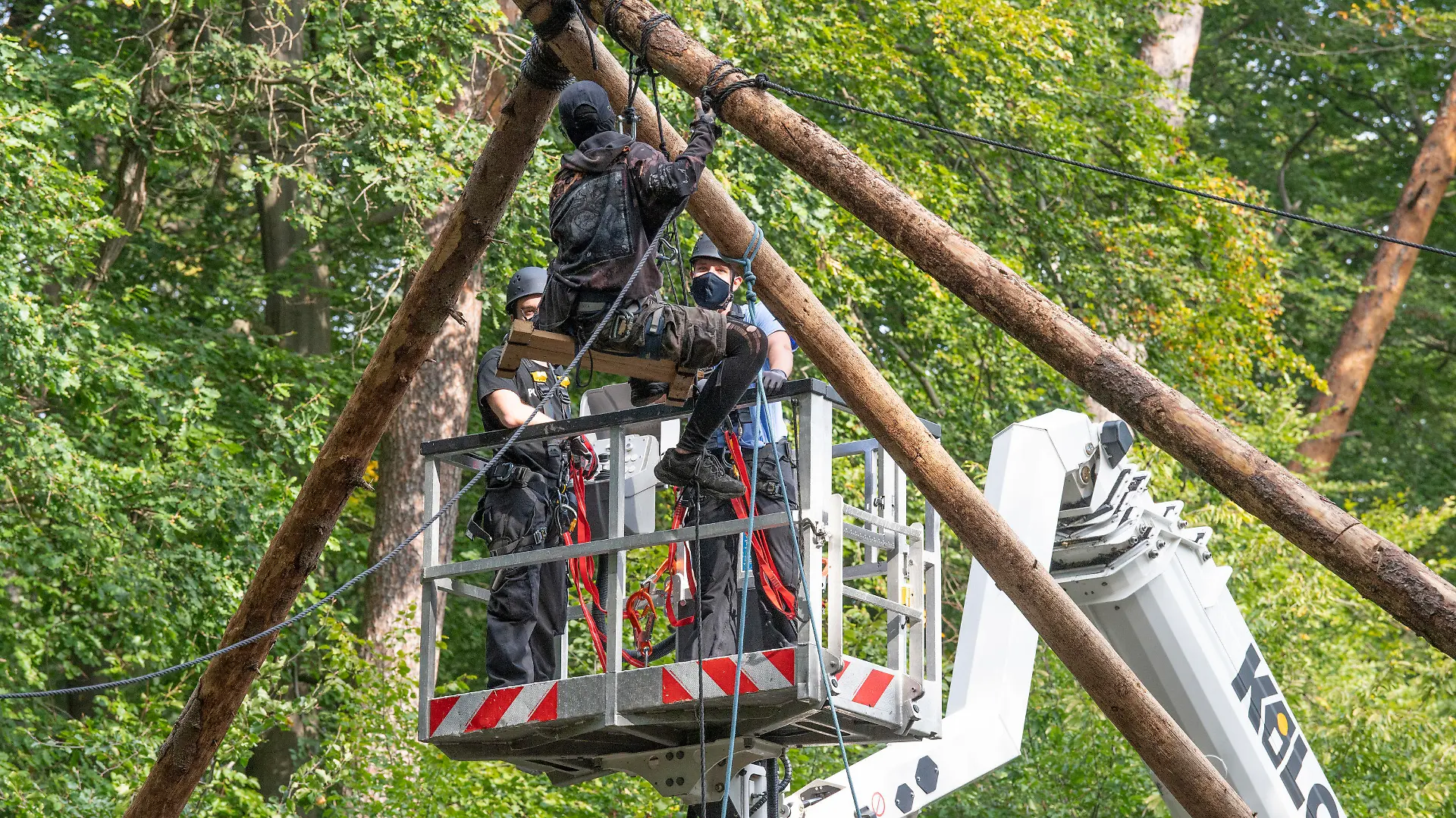 16.09.2020, Hessen, Dannenrod: Die Polizei räumt Barrikaden von Waldbesetzern im Dannenröder Forst in Mittelhessen. Eine Aktivistin sitzt auf einer aus Stämmen errichteten Plattform, während Polizisen von einer Hebenbühne aus versuchen sie zu erreichen. Die Waldbesetzer protestieren gegen den Ausbau der Autobahn 49. Foto: Boris Roessler/dpa +++ dpa-Bildfunk +++