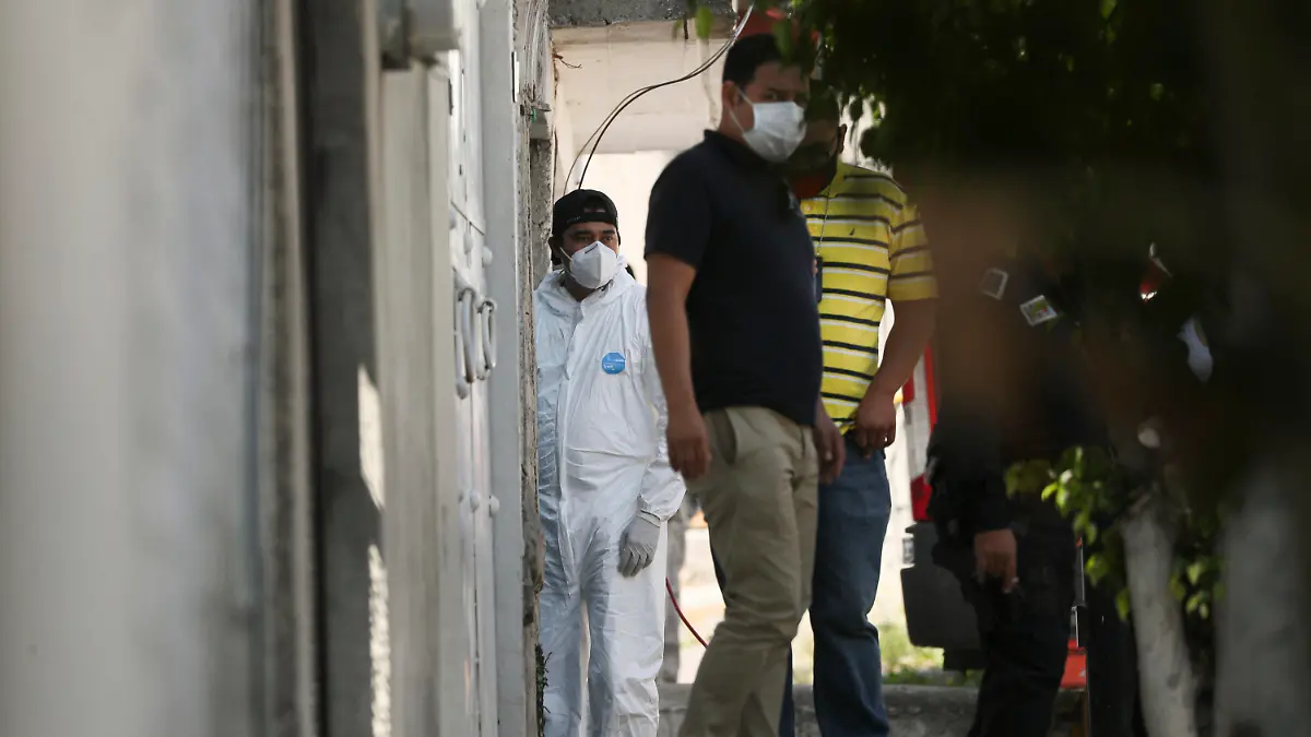 A forensic investigator stands at the entrance of a house where police found bones under the floor in the Atizapan municipality of the State of Mexico, Thursday, May 20, 2021. Police have turned up bones and other evidence under the floor of the house where a man was arrested for allegedly stabbing a woman to death and hacking up her body. (AP Photo/Fernando Llano)