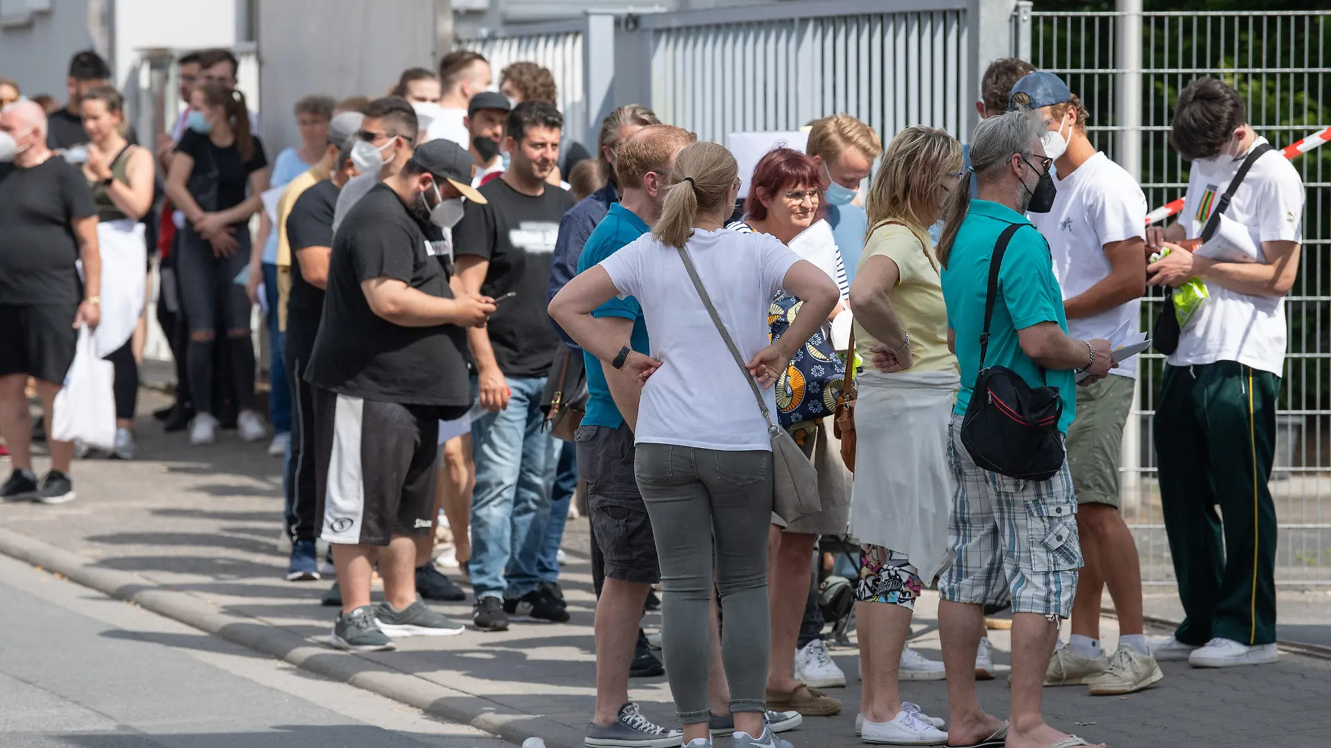 12.06.2021, Hessen, Babenhausen: Insgesamt mehr als 1500 Menschen warten bei sommerlichen Temperaturen im Freien auf Einlass in eine Arztpraxis im hessischen Babenhausen. Ein Hausarzt hatte hier 1000 Impfdosen Impfdosen erhalten und zu einem ·offenen Impftag· für Corona-Schutzimpfungen aufgerufen. Ein Teil der Impfwilligen hatte auf dem Bürgersteig vor der Praxis übernachtet. Foto: Boris Roessler/dpa - ACHTUNG: Verwendung nur im vollen Format +++ dpa-Bildfunk +++