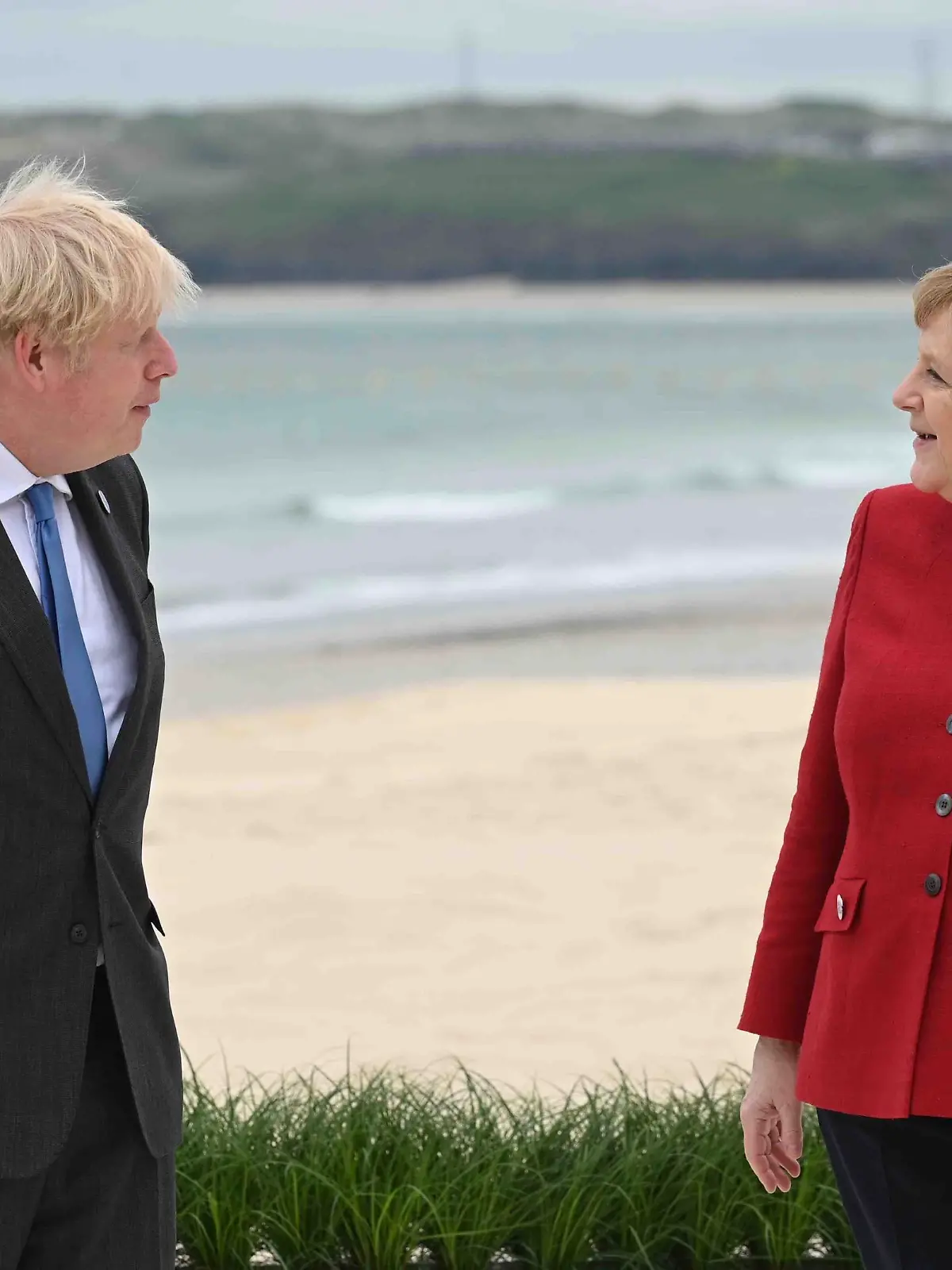 Britain's Prime Minister Boris Johnson, speaks to Germany's Chancellor Angela Merkel during the Leaders official welcome and group photo session, during the G7 Summit in Carbis Bay, Cornwall, England, Friday, June 11, 2021. (Leon Neal/Pool Photo via AP)