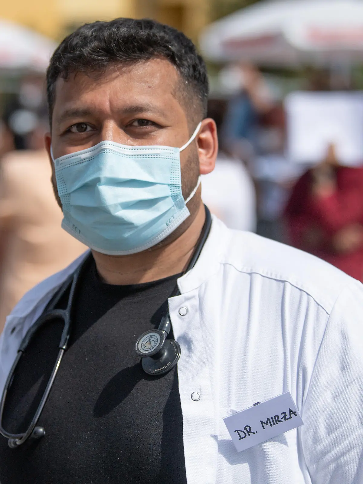 12.06.2021, Hessen, Babenhausen: Abrar Mirza geht im Innenhof an wartenden Impfwilligen vorbei. Der Hausarzt hatte hier 1000 Impfdosen Impfdosen erhalten und zu einem ·offenen Impftag· für Corona-Schutzimpfungen aufgerufen. Ein Teil der Impfwilligen hatte auf dem Bürgersteig vor der Praxis übernachtet. Foto: Boris Roessler/dpa +++ dpa-Bildfunk +++