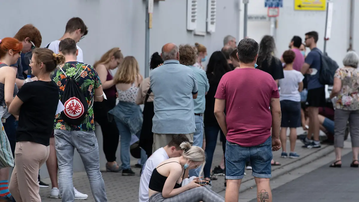 12.06.2021, Hessen, Babenhausen: Insgesamt mehr als 1500 Menschen warten bei sommerlichen Temperaturen im Freien auf Einlass in eine Arztpraxis im hessischen Babenhausen. Ein Hausarzt hatte hier 1000 Impfdosen Impfdosen erhalten und zu einem ·offenen Impftag· für Corona-Schutzimpfungen aufgerufen. Ein Teil der Impfwilligen hatte auf dem Bürgersteig vor der Praxis übernachtet. Foto: Boris Roessler/dpa - ACHTUNG: Verwendung nur im vollen Format +++ dpa-Bildfunk +++