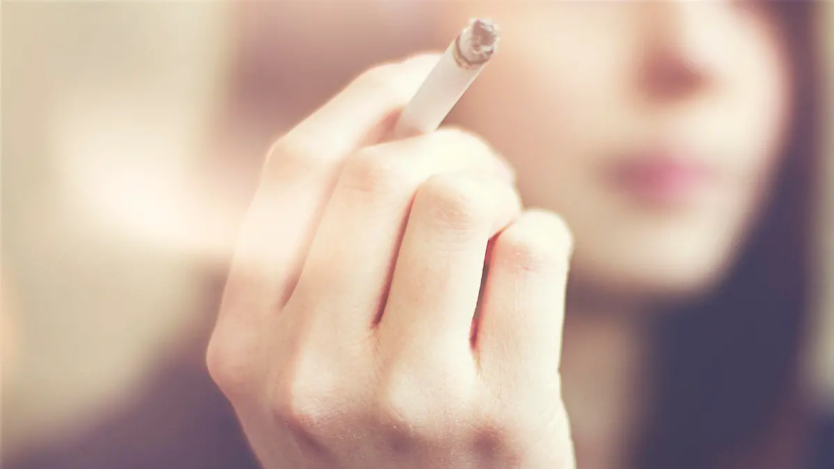 Woman hands holding cigarette outdoor.