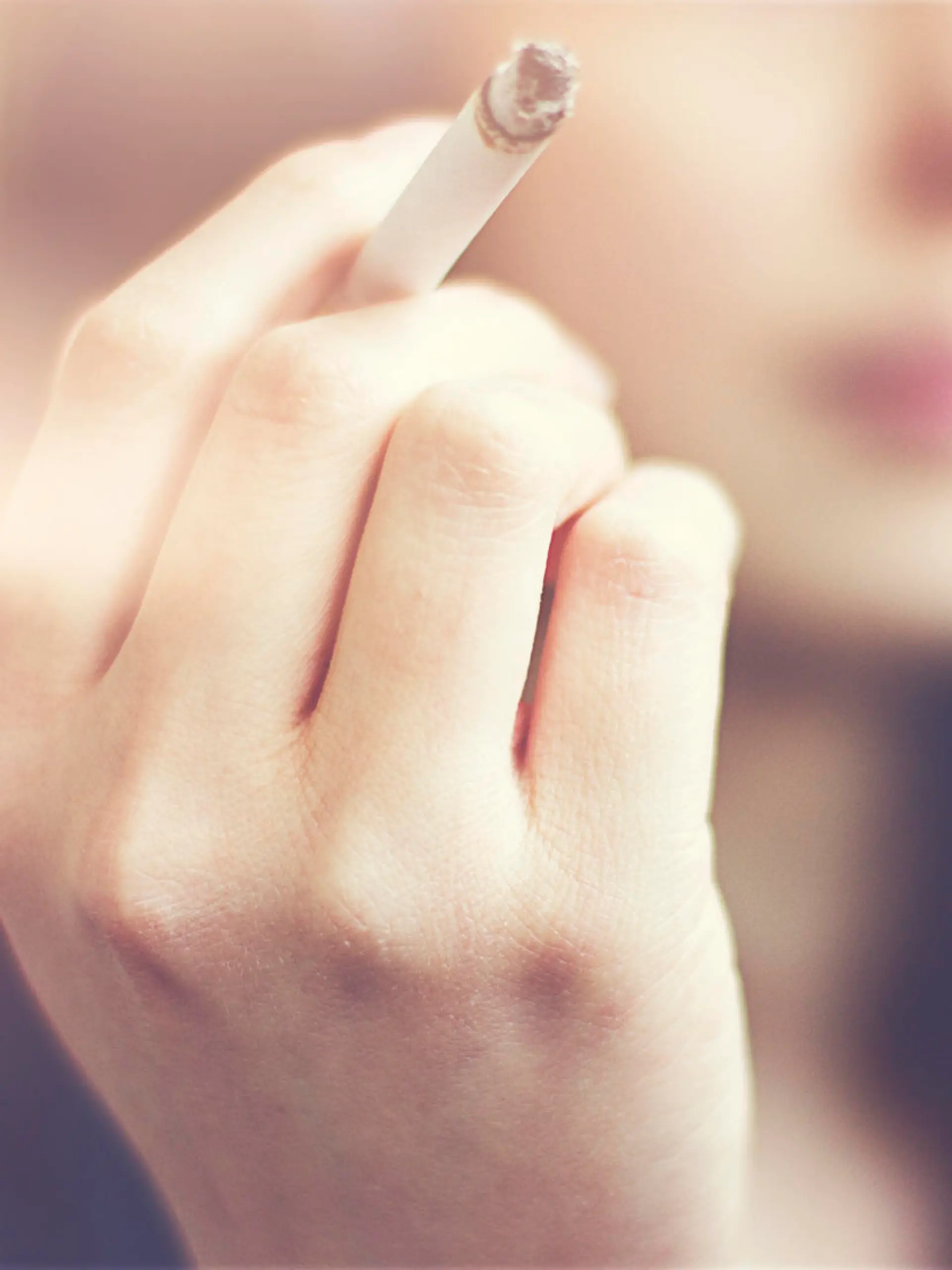 Woman hands holding cigarette outdoor.