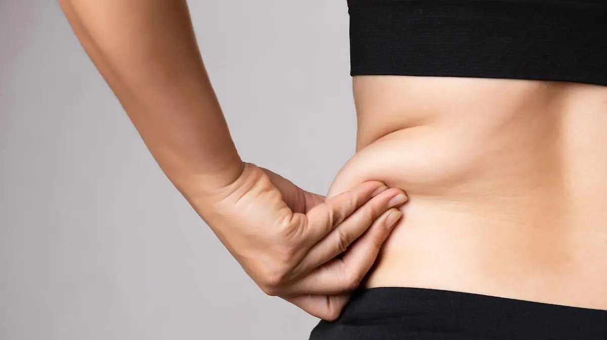 Fat woman hand holding excessive belly fat. Healthcare and woman diet lifestyle concept to reduce belly and shape up healthy stomach muscle.