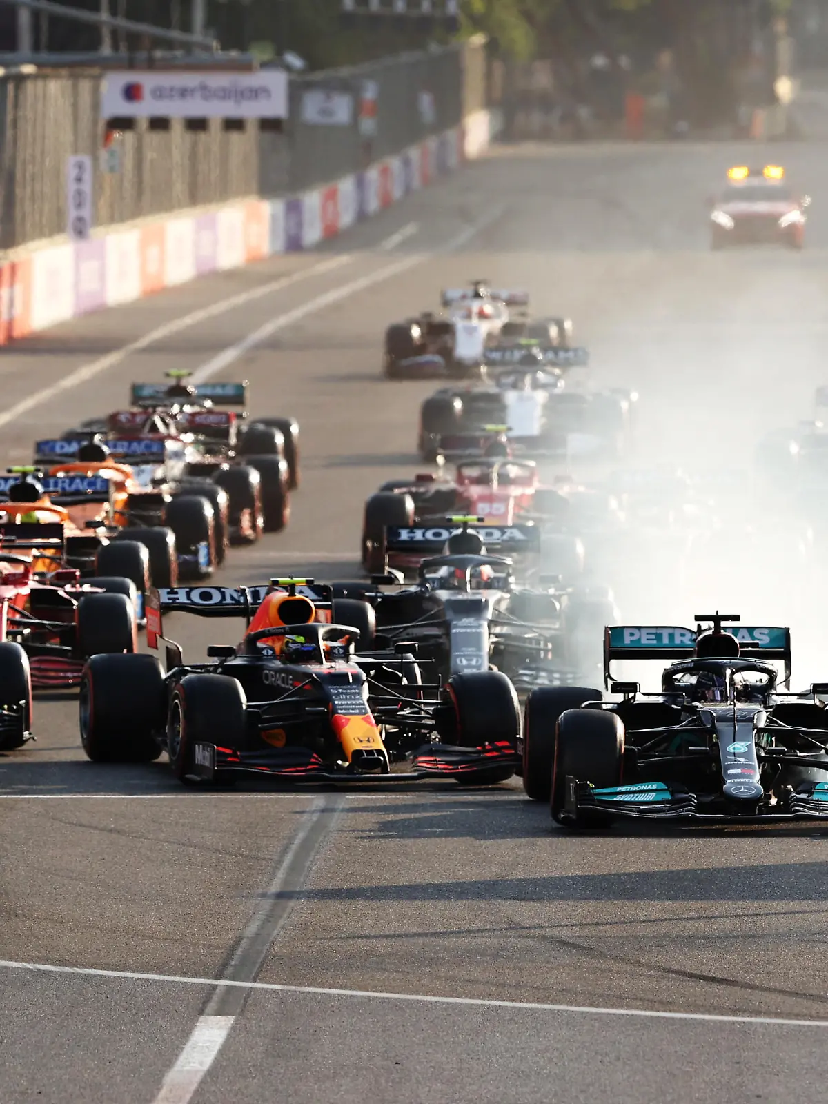 BAKU, AZERBAIJAN - JUNE 06: Lewis Hamilton of Great Britain driving the (44) Mercedes AMG Petronas F1 Team Mercedes W12 locks up under pressure from Sergio Perez of Mexico driving the (11) Red Bull Racing RB16B Honda into the first corner after the restart following a red flag period during the F1 Grand Prix of Azerbaijan at Baku City Circuit on June 06, 2021 in Baku, Azerbaijan. (Photo by Clive Rose/Getty Images)