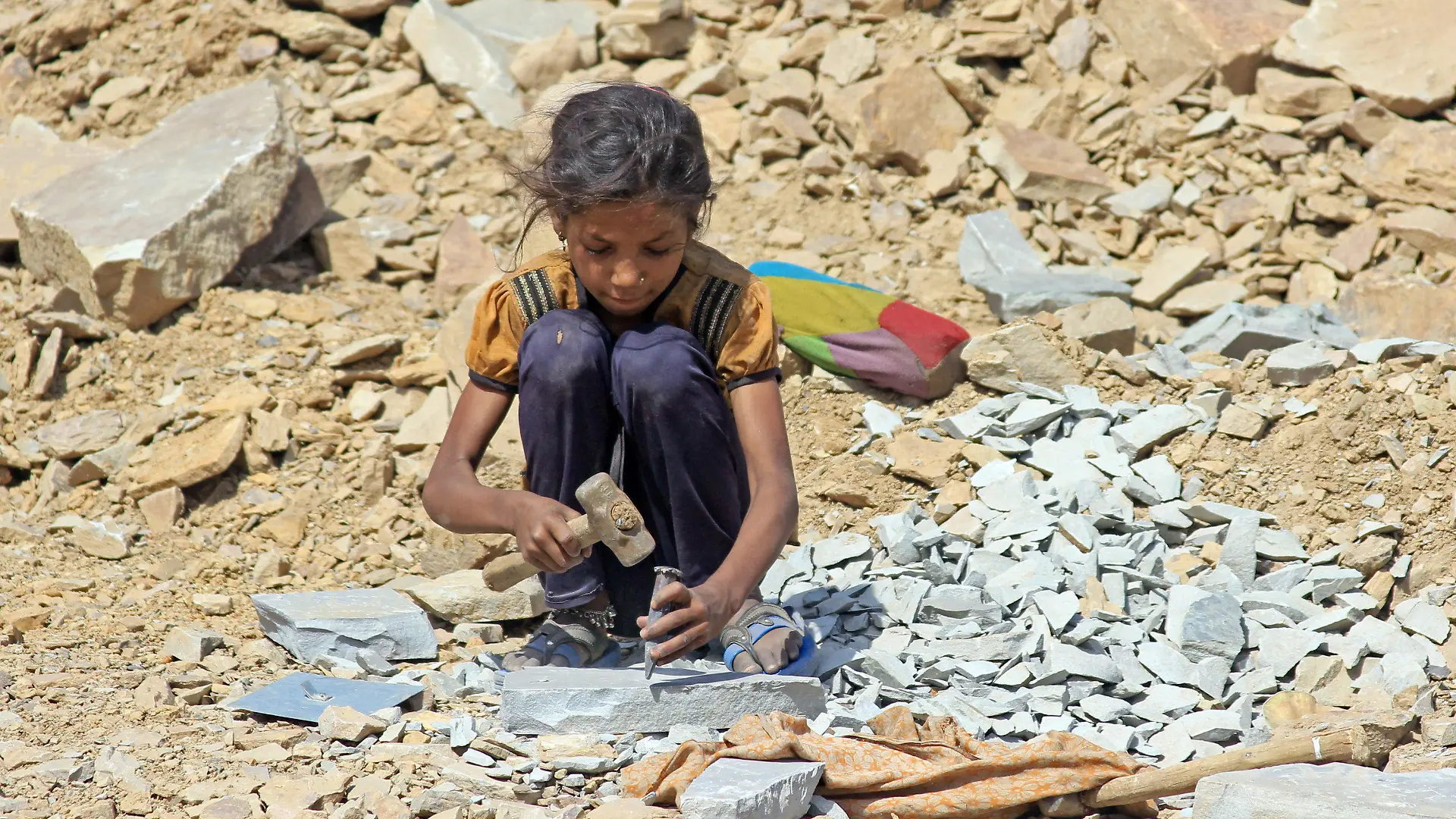 Die etwa 8-jährige Sunita sitzt am 16.05.2013 in Kota, in der indischen Provinz Rajasthan, in einem Steinbruch und arbeitet mit Hammer und Meißel. Tausende Kinder hauen in Steinbrüchen in Indien Pflastersteine für den europäischen Markt. Foto: Doreen Fiedler/dpa (zu dpa "Kleine Hände hauen in Indien Pflastersteine für Europa" vom 11.06.2013) +++(c) dpa - Bildfunk+++