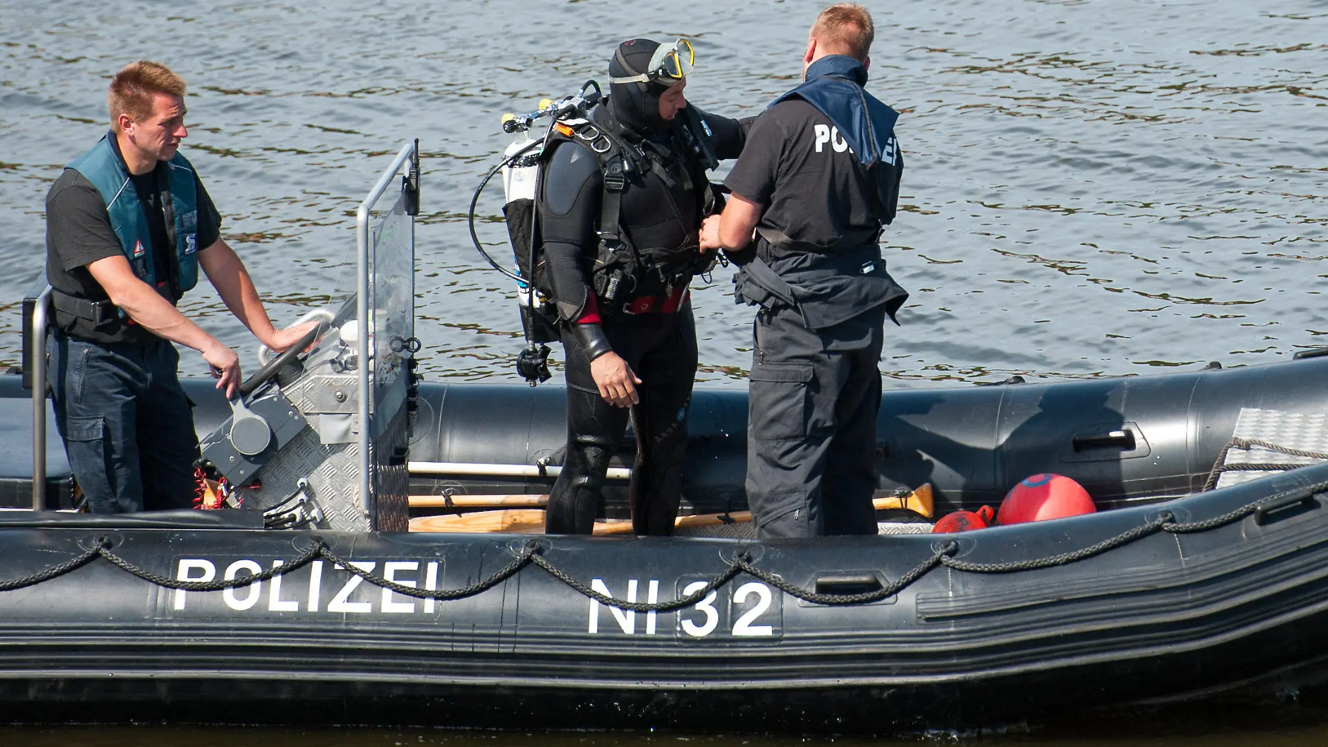 ARCHIV - Ein Taucher (M) der Polizei bereitet sich auf einem Boot am 01.08.2015 bei Hohnstorf/Elbe (Niedersachsen) auf seinen Einsatz vor. Nach dem Fund der Leiche des Familienvaters sucht die Polizei weiter nach der ebenfalls vermissten Mutter und Tochter. Knapp drei Wochen nach dem Verschwinden einer Familie in Drage sucht die Polizei nun auch mit Hilfe von «Aktenzeichen XY... ungelöst» nach Zeugen. Foto: Philipp Schulze/dpa (zu lni "Vermisstenfall von Drage bei «Aktenzeichen XY... ungelöst»" vom 10.08.2015) +++(c) dpa - Bildfunk+++